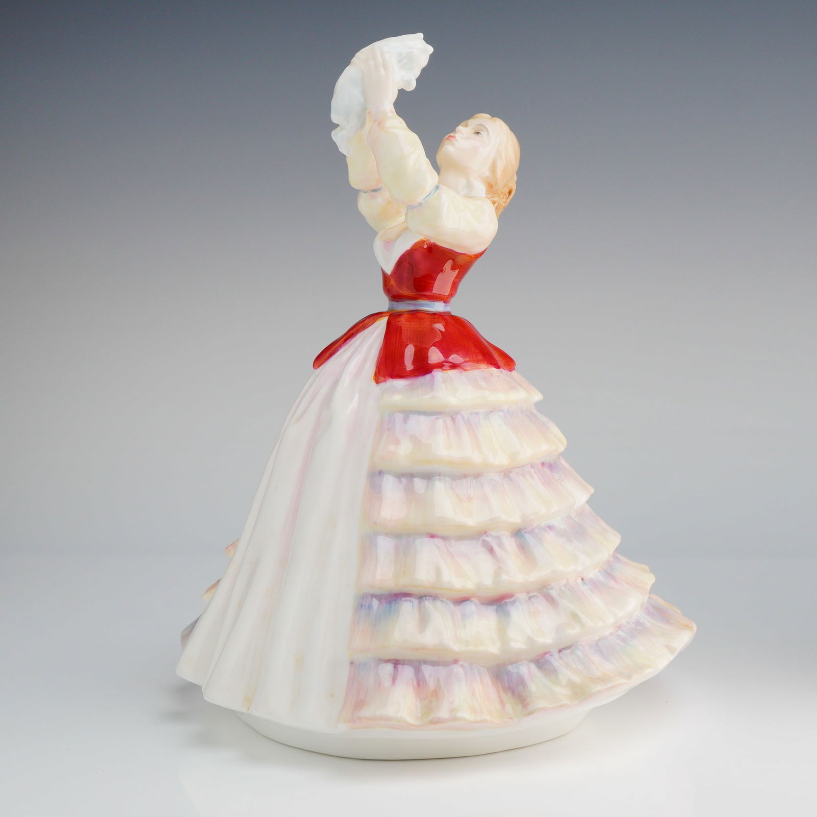 Royal Doulton Figurine, Susan HN3050: The figure depicts a young woman in a formal, voluminous tiered gown with a high-gloss finish. The bodice is rendered in high-gloss red glaze, contrasting with the multi-colored pastel ruffled skirt.