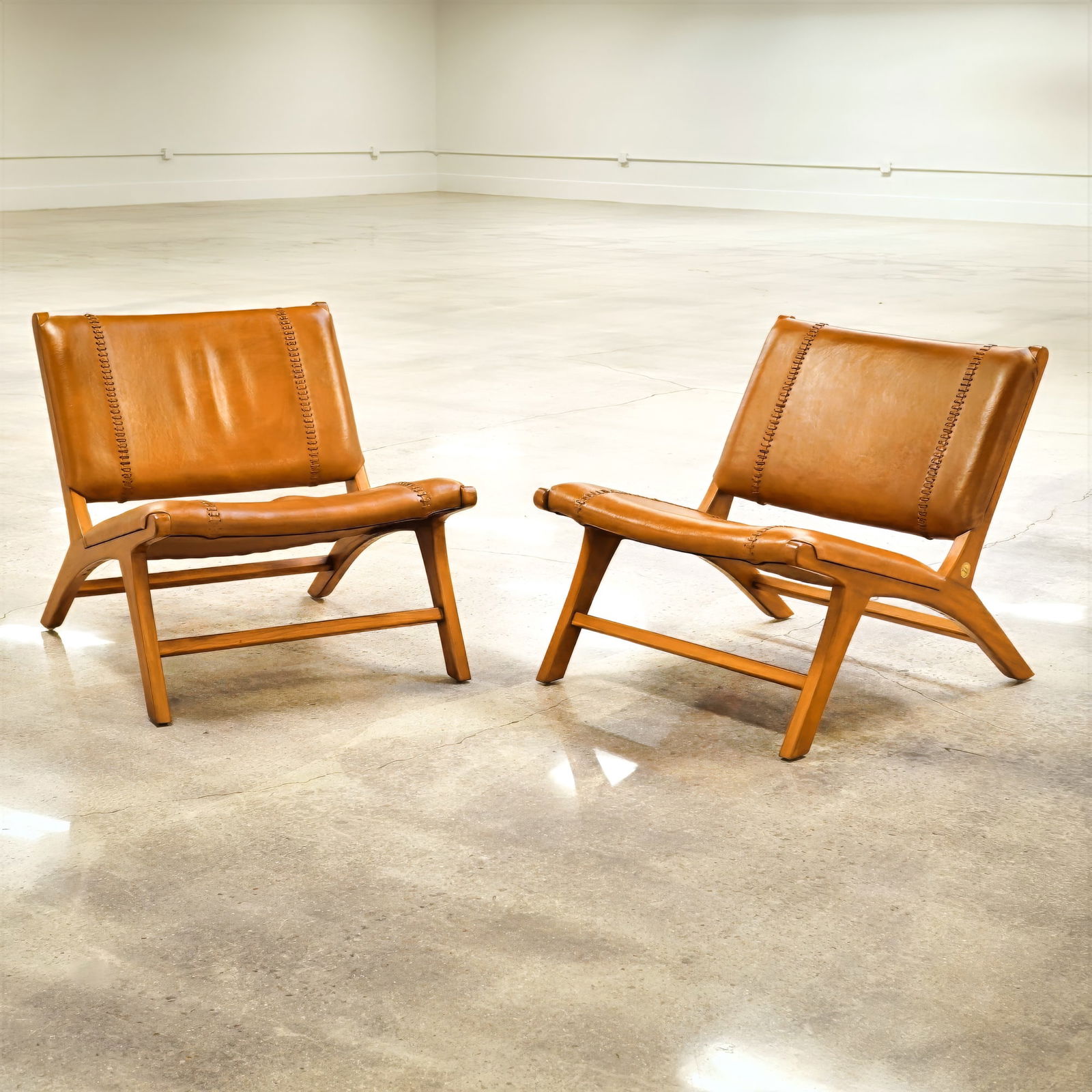 Pair of Olivier De Schrijver Relax Chairs in Natural Leather, Cowboy: A pair of Olivier De Schrijver relax lounge chairs titled "Cowboy", featuring solid teak wood frames and brown natural leather upholstery. These mid-century modern style chairs are designed with low-s
