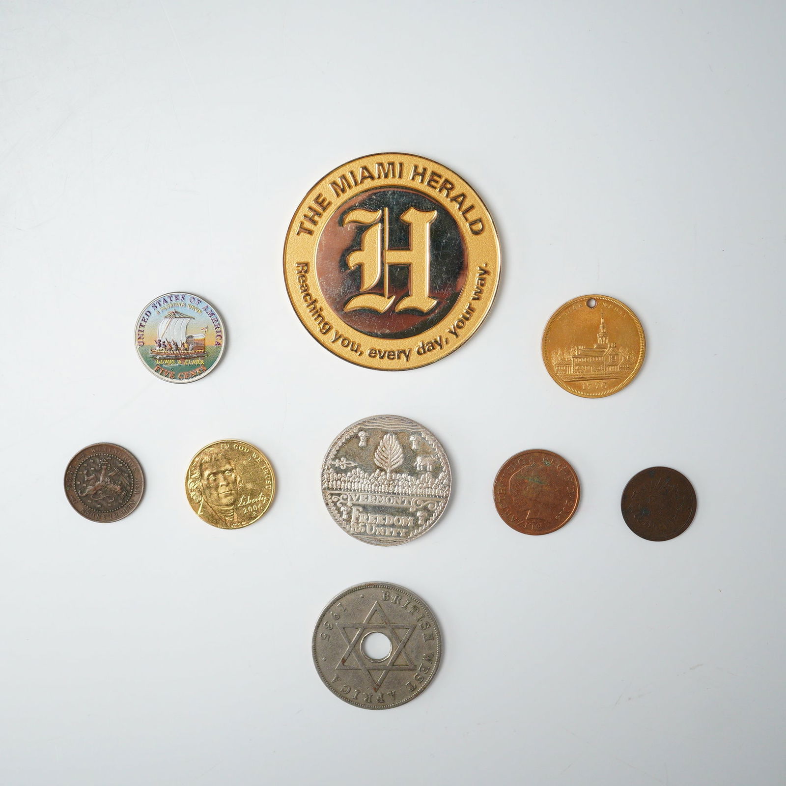9pc 1935 - 2006 United States and World Coins and Tokens: This collection features a varied mix of historic and modern coins alongside commemorative tokens from the United States and abroad. Included are a gold Gulfstream Park and Miami Herald token issued f