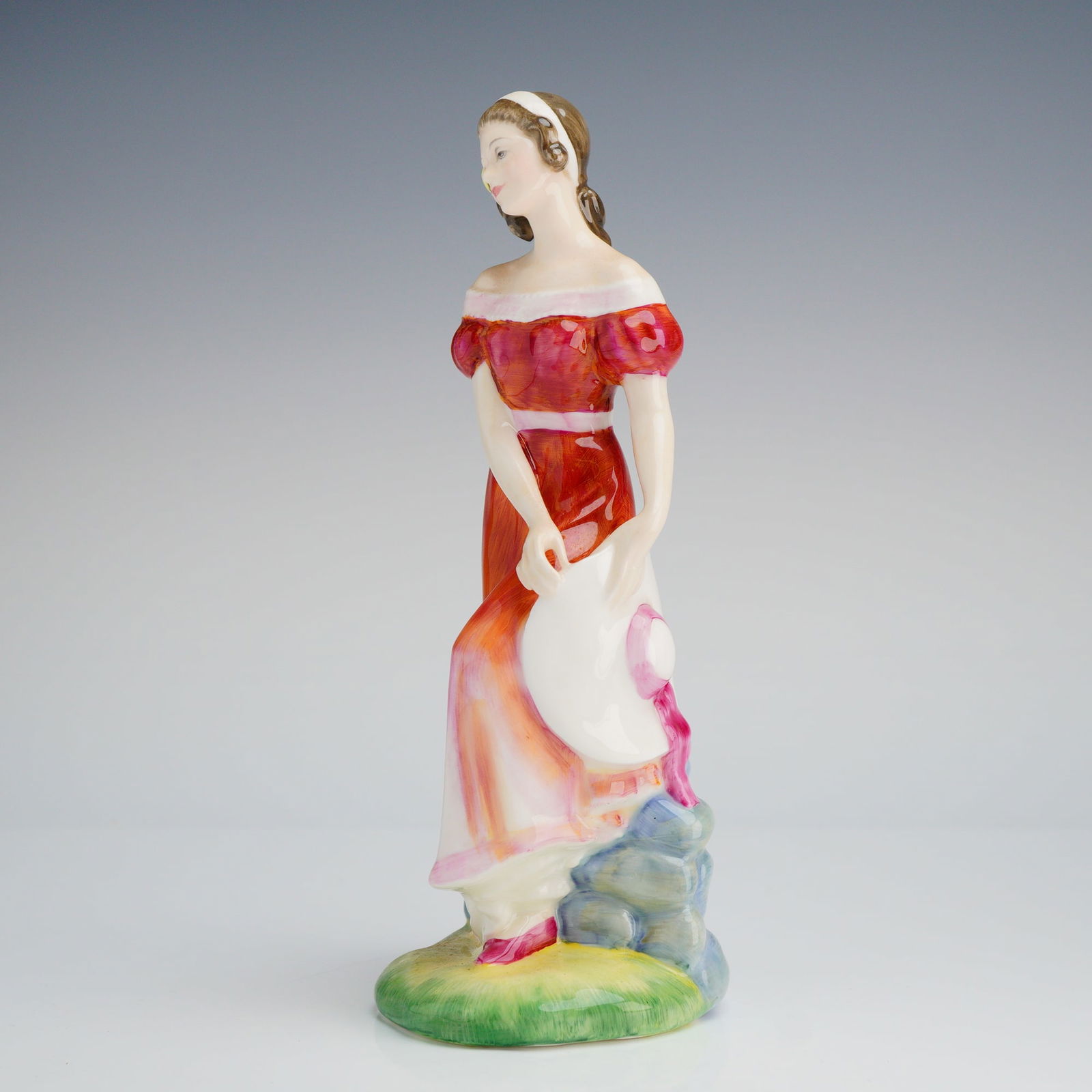 Royal Doulton Figurine, Jemma HN3168: The figure was modelled by Peggy Davies and copyrighted 1987. The figurine portrays a young woman standing in a flowing, off-the-shoulder red dress, holding a wide-brimmed white hat, and leaning again
