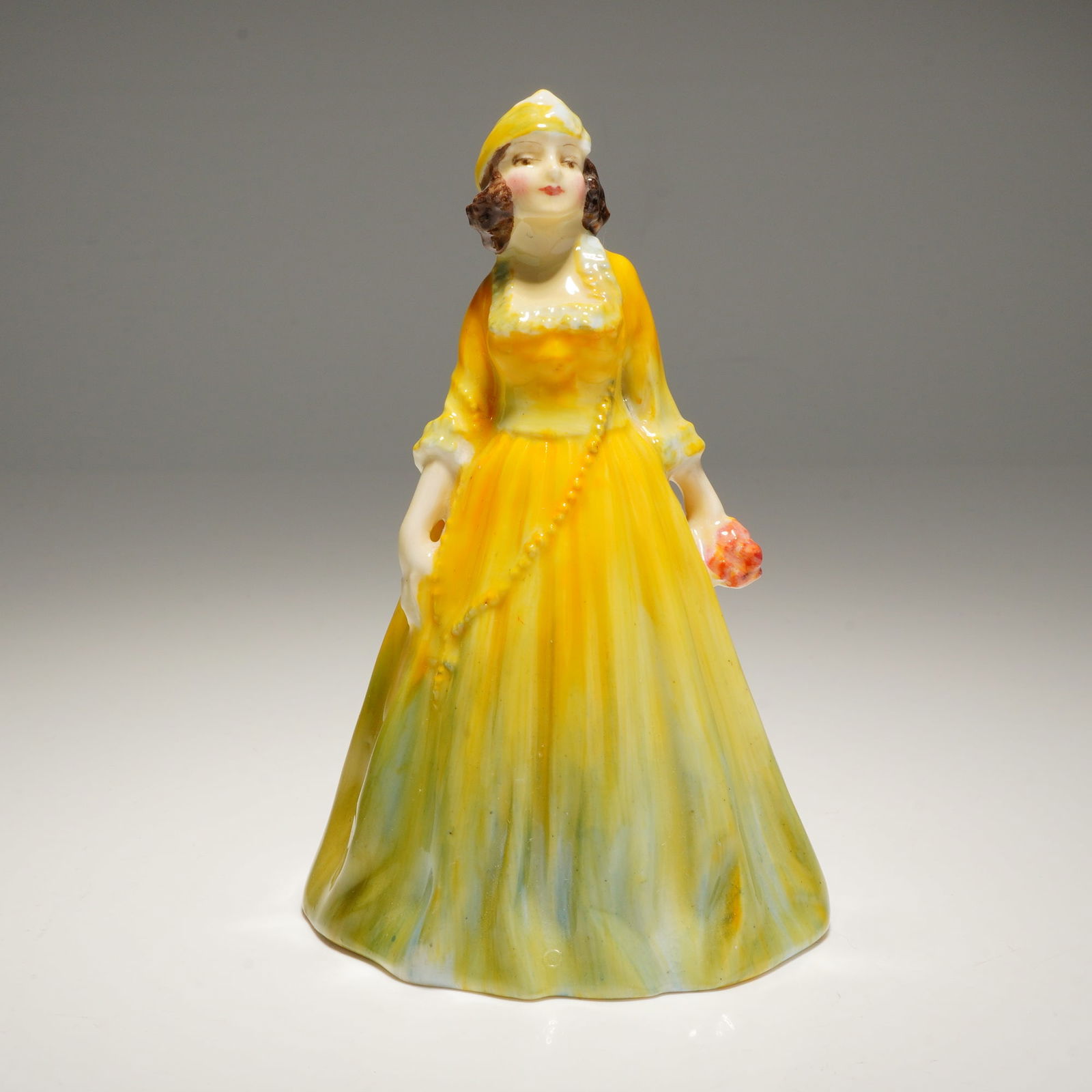 Royal Doulton Miniature Figurine Rosamund M32: A yellow and green ceramic figurine identified as Rosamund M32 Royal Doulton Figurine, marked "By Royal Doulton" and stamped "MADE IN ENGLAND ROYAL DOULTON BONE CHINA" on the base. Dimensions: 3.00"L