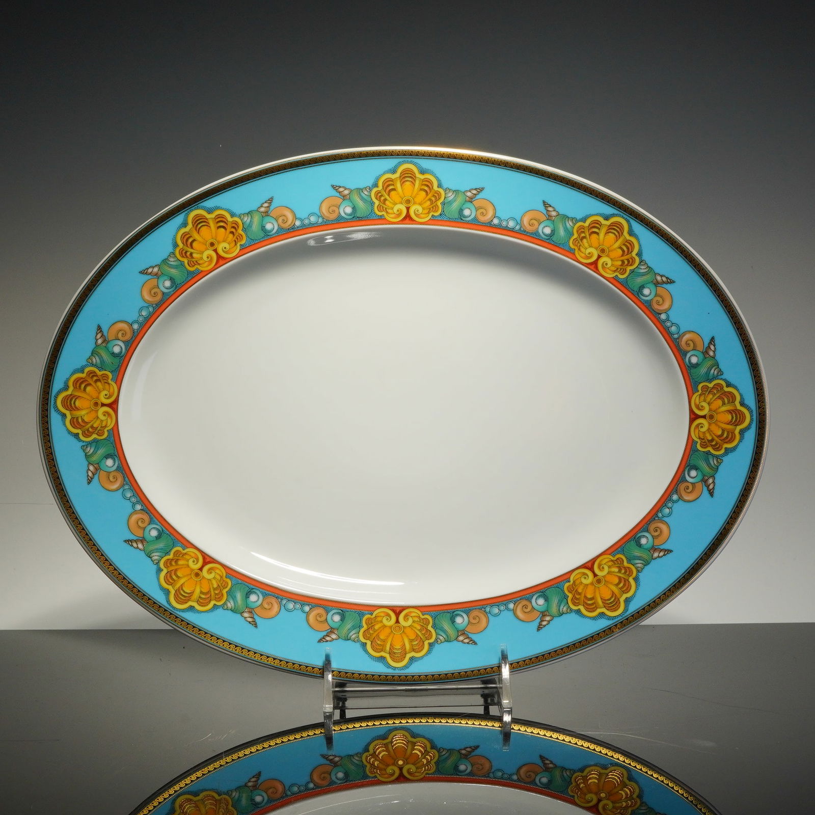 Rosenthal Versace Oval Serving Platter, Les Tresors de la Mer: This Rosenthal Versace Platter features a turquoise-blue border decorated with stylized seashells and pearls in shades of yellow, orange, and green. The design is accented by a gilded rim and an inner