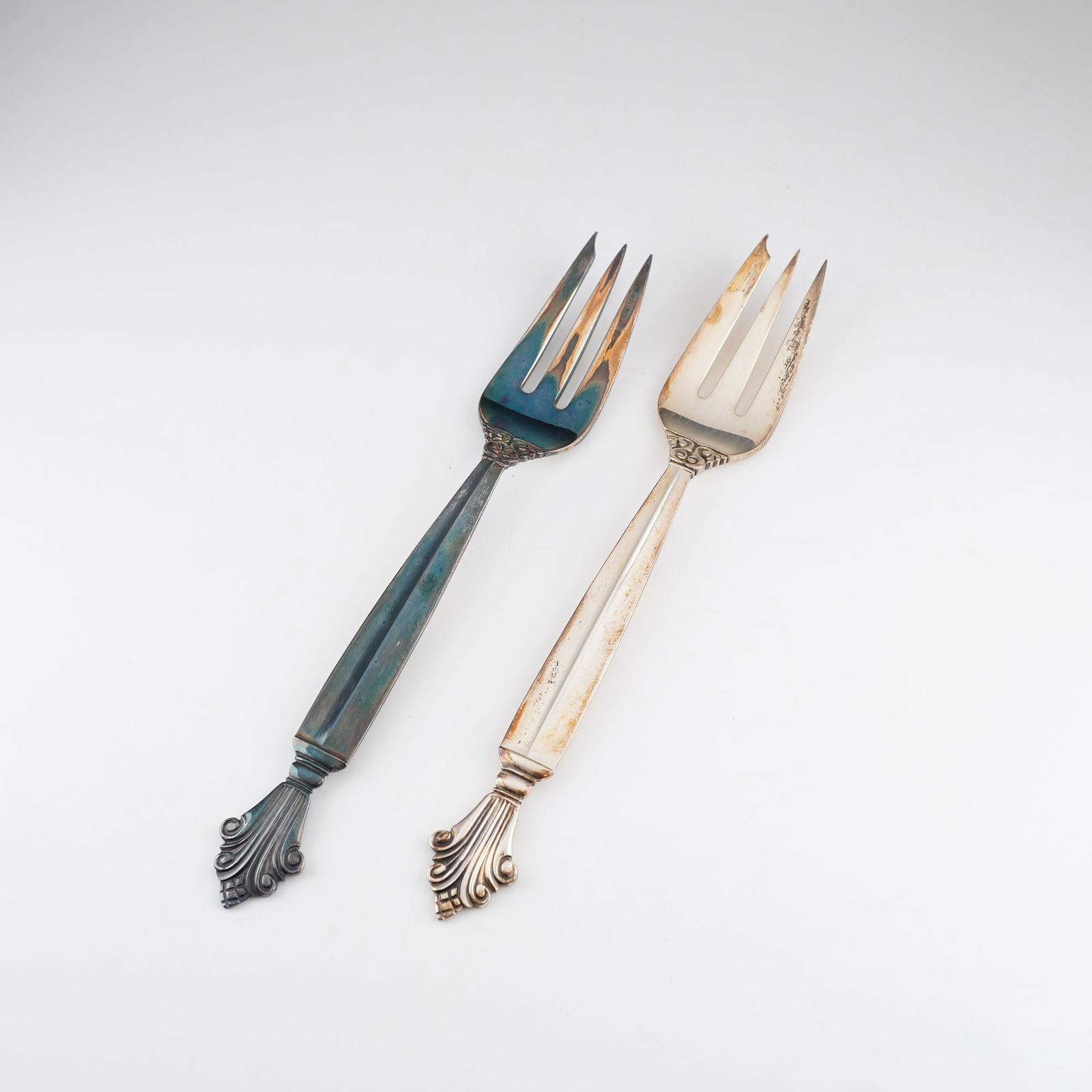 2pc Georg Jensen Sterling Silver Pastry Forks, Acanthus: A pair of Georg Jensen sterling silver pastry forks in the Acanthus pattern, designed by Johan Rohde. Each three-tine fork features a faceted handle terminating in a decorative acanthus leaf and