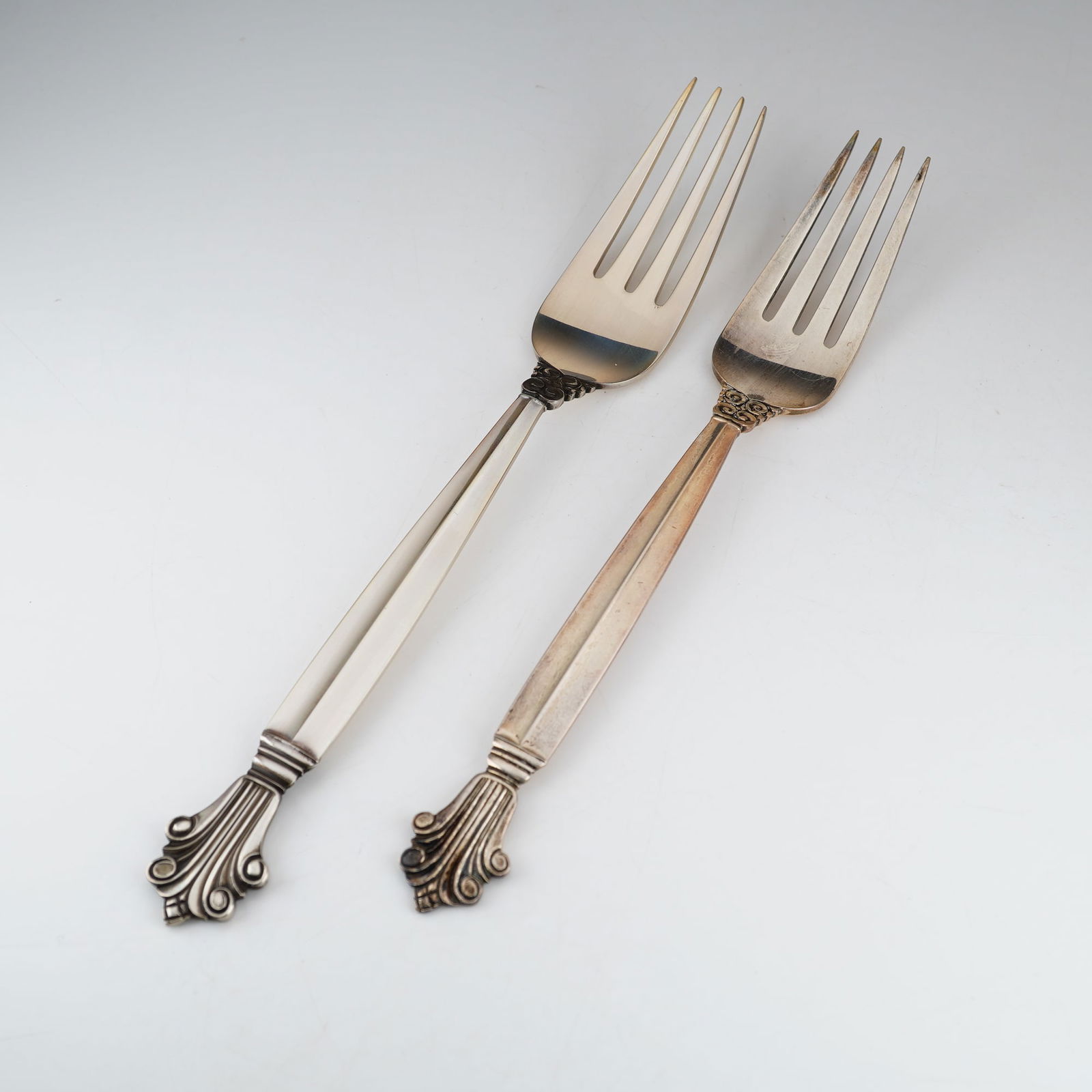 2pc Georg Jensen Sterling Silver Forks, Acanthus: A pair of sterling silver forks in the Acanthus pattern by Georg Jensen. Originally designed by Johan Rohde in 1917, the pattern is characterized by a faceted handle that tapers toward a decorative fi