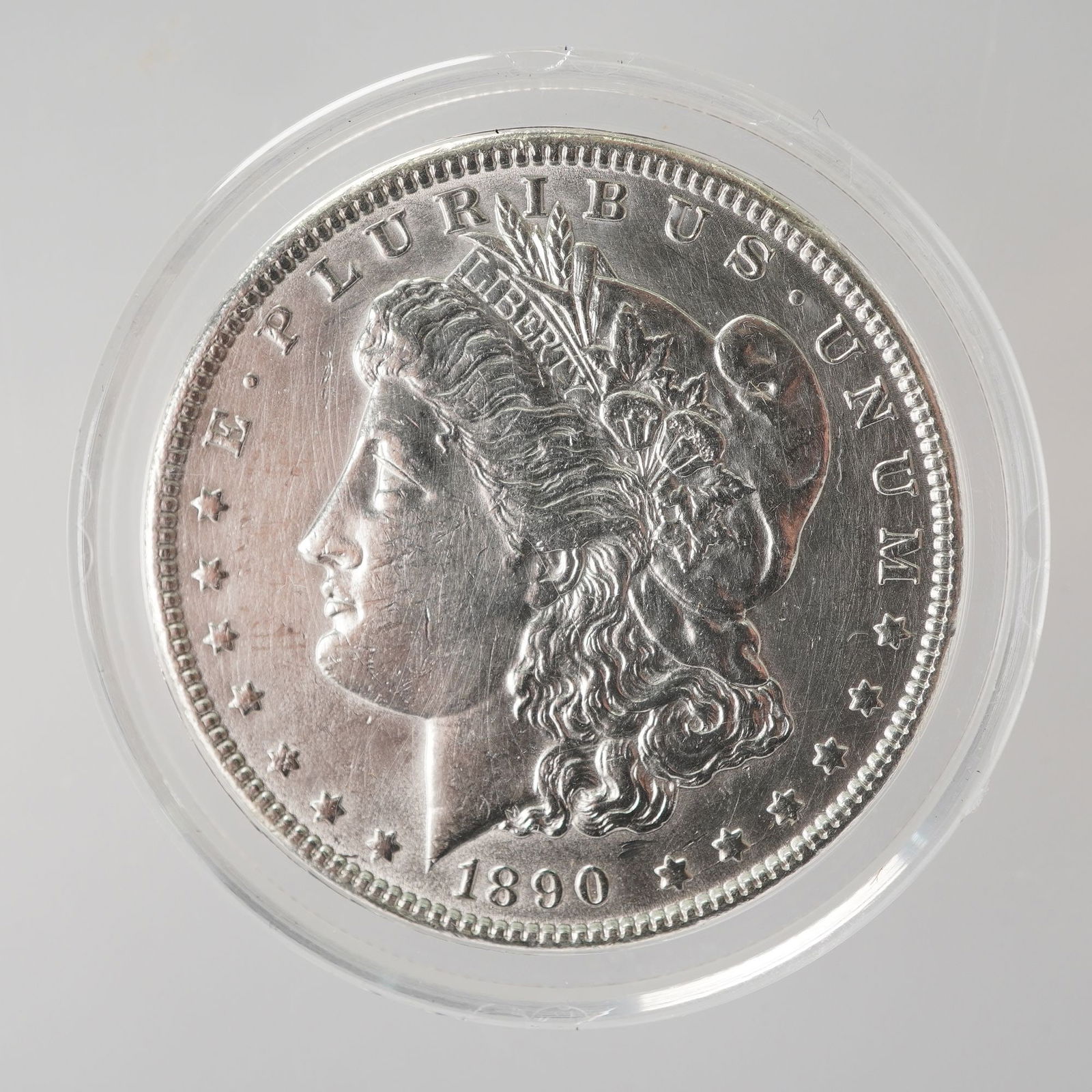 1890 Morgan Silver Dollar: Features the classic profile of Lady Liberty on the obverse, wearing a Phrygian cap adorned with wheat and cotton, symbolizing freedom and agricultural prosperity. Surrounding her are thirteen stars,