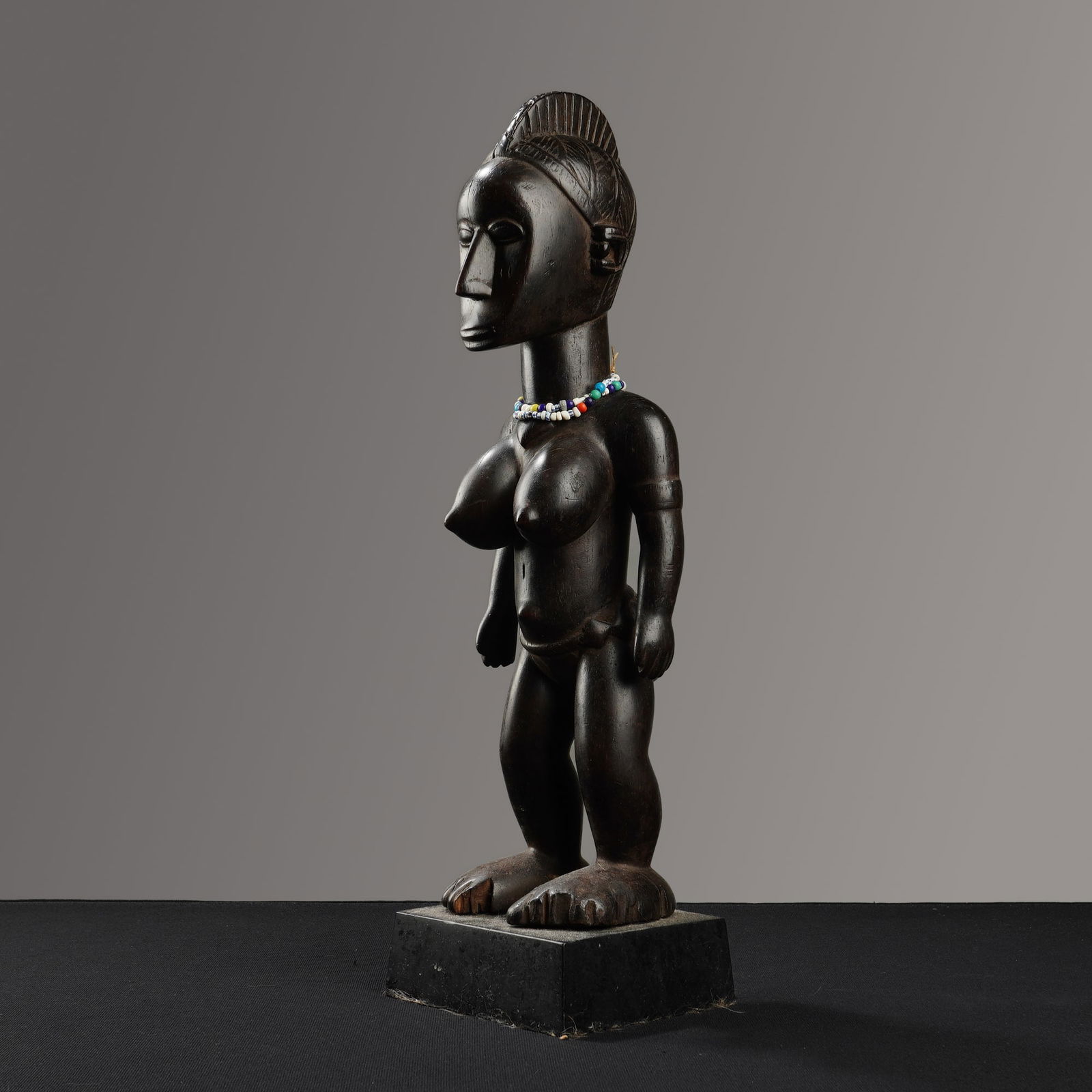 African Baule Hand-Carved Wooden Fertility Sculpture: This hand-carved wooden African Boule fertility sculpture, originating from the Baule people of Cote d'Ivoire, depicts a standing female figure often identified as a Blolo Bla or spirit spouse. The