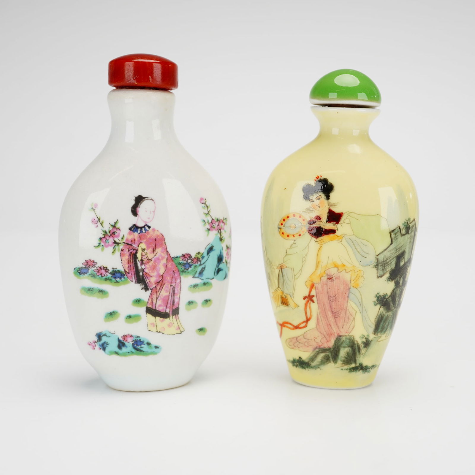2pc Chinese Hand-Painted Porcelain Snuff Bottles: A group of hand-painted Chinese porcelain snuff bottles of flattened ovoid form. The first bottle features a white glaze ground decorated with a female figure in a garden setting on the obverse and a