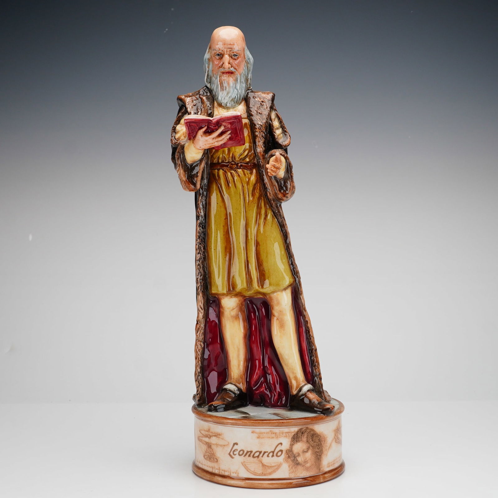 Royal Doulton Figurine, Leonardo Da Vinci HN4939: This hand-made and hand-decorated limited edition, 25 of 250, figure depicts the Renaissance polymath with a long gray beard, holding an open red book and wearing a fur-trimmed brown robe over a yello