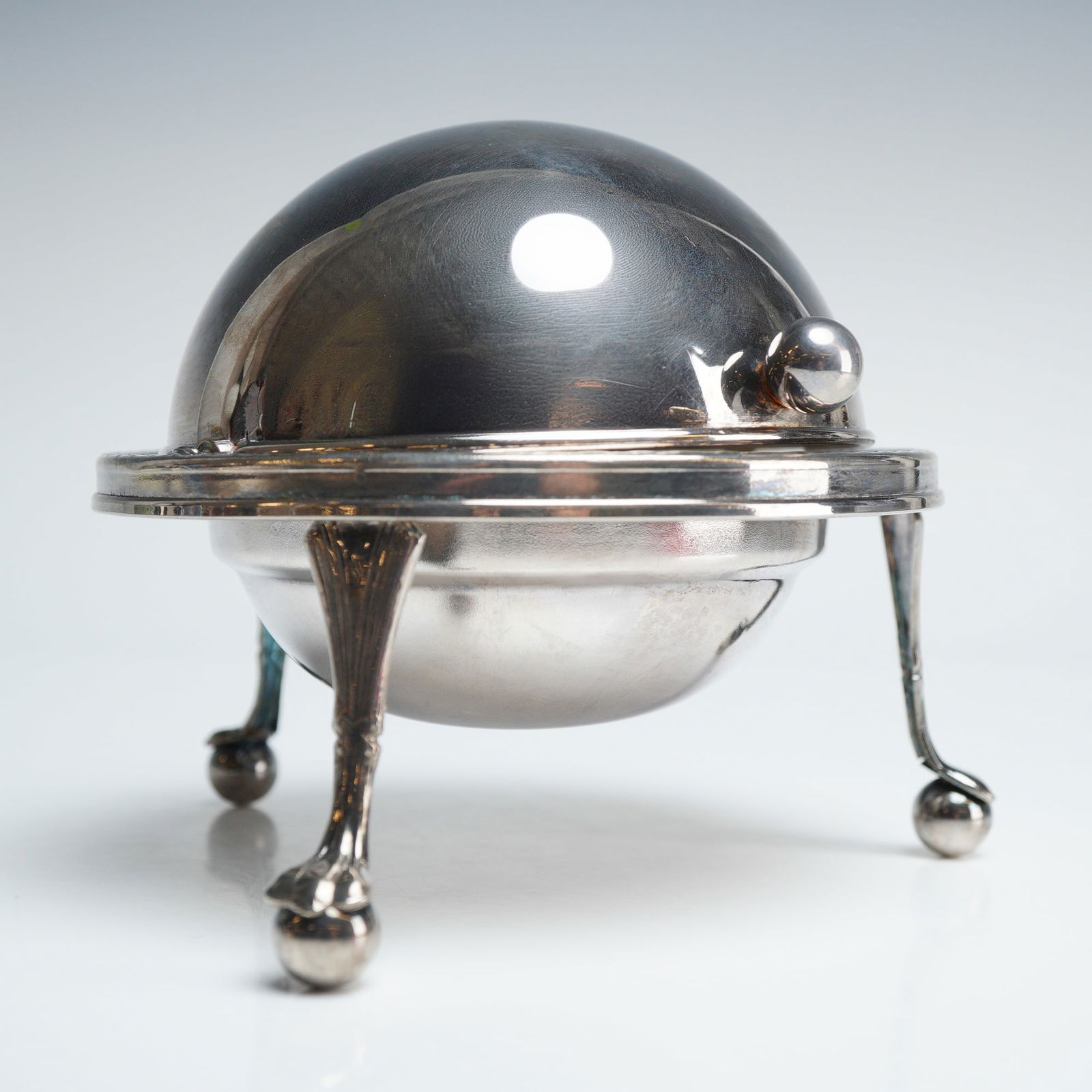 Silver Plated Roll Top Caviar Dish: A silver plated roll top caviar dish or rotating butter dish of spherical form. The piece features a rotating dome lid with a small spherical finial and a wide horizontal flange encircling the midsect