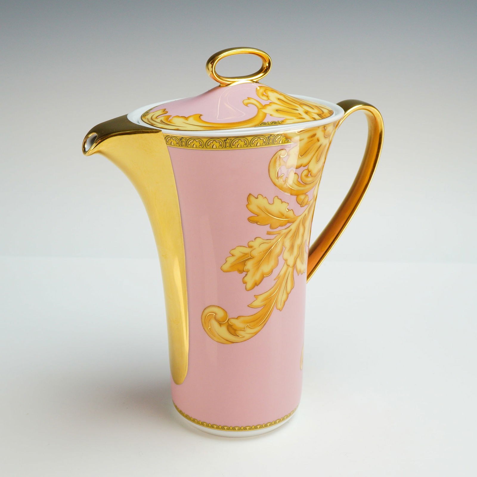 Versace Rosenthal Porcelain Lidded Coffee Pot, Les Reves Byzantins: This tall, slender vessel features a pale pink ground accented with gilded acanthus leaf and baroque scrollwork throughout. The piece is finished with a fully gilded spout and curved handle, and