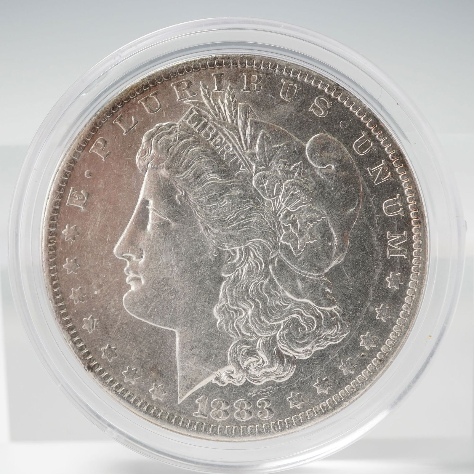 1883-O Morgan Silver Dollar: Struck at the New Orleans Mint, this classic coin features the celebrated Liberty head design on the obverse, with the word LIBERTY inscribed upon a coronet and surrounded by E PLURIBUS UNUM and