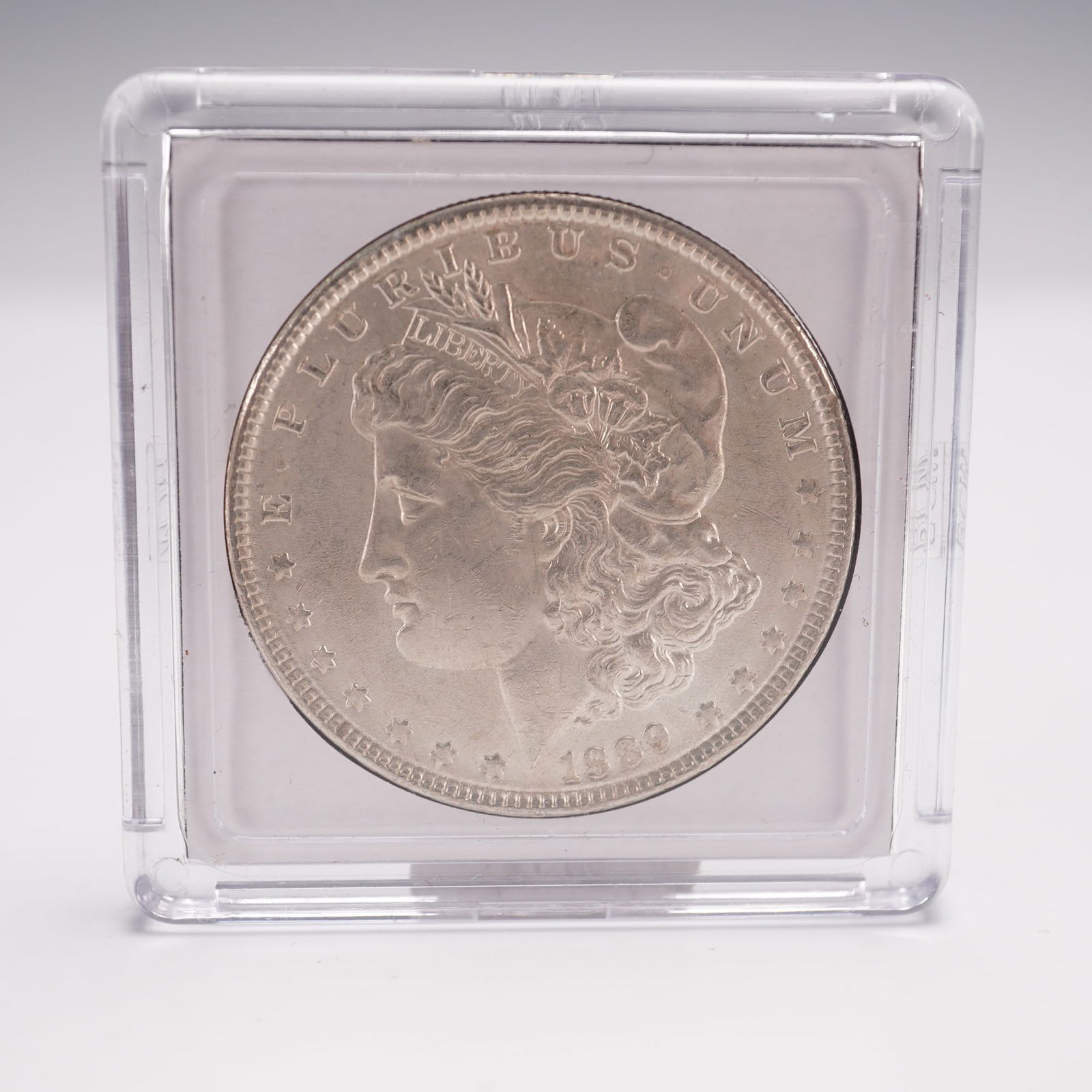1889 Morgan Silver Dollar: The obverse features the profile of Liberty facing left, with the inscription E PLURIBUS UNUM above and the date 1889 below, surrounded by thirteen stars. The reverse depicts a detailed eagle with