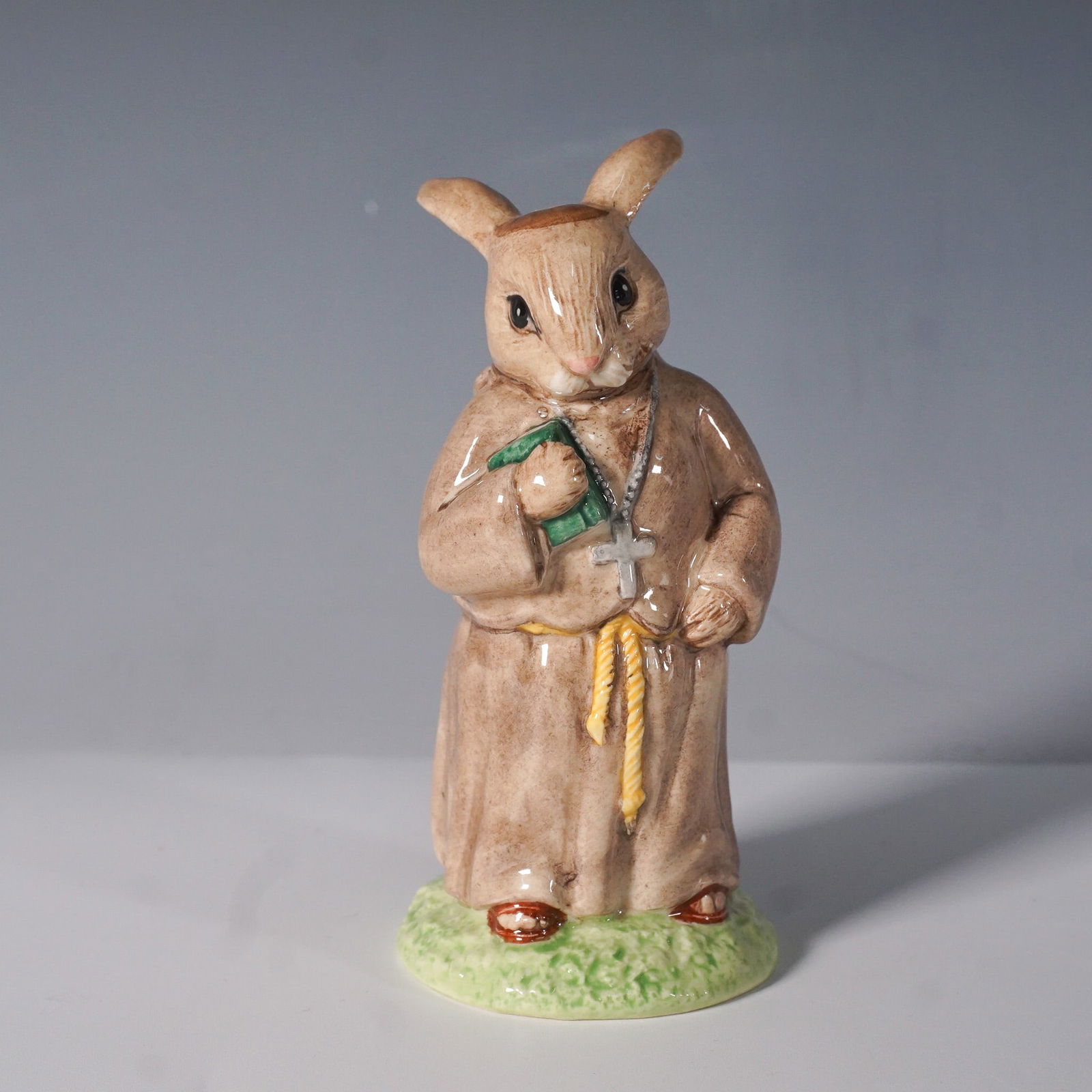 Royal Doulton Bunnykins Figurine, Friar Tuck DB 246: Charming Royal Doulton Bunnykins figurine titled Friar Tuck, DB 246, from the Robin Hood Collection. This finely crafted figurine features a brown-robed bunny holding a book and rosary, embodying the