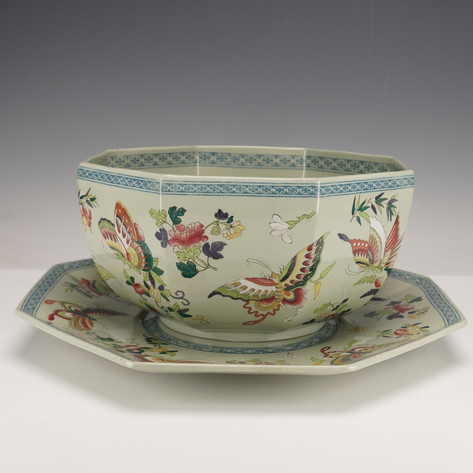 2pc Wedgwood Etruria Chinoiserie Butterfly Bowl and Saucer: The English octagonal bowl and matching underplate are decorated in a chinoiserie style, each featuring a celadon-tone ground with polychrome enamel decoration of butterflies and scattered floral spra