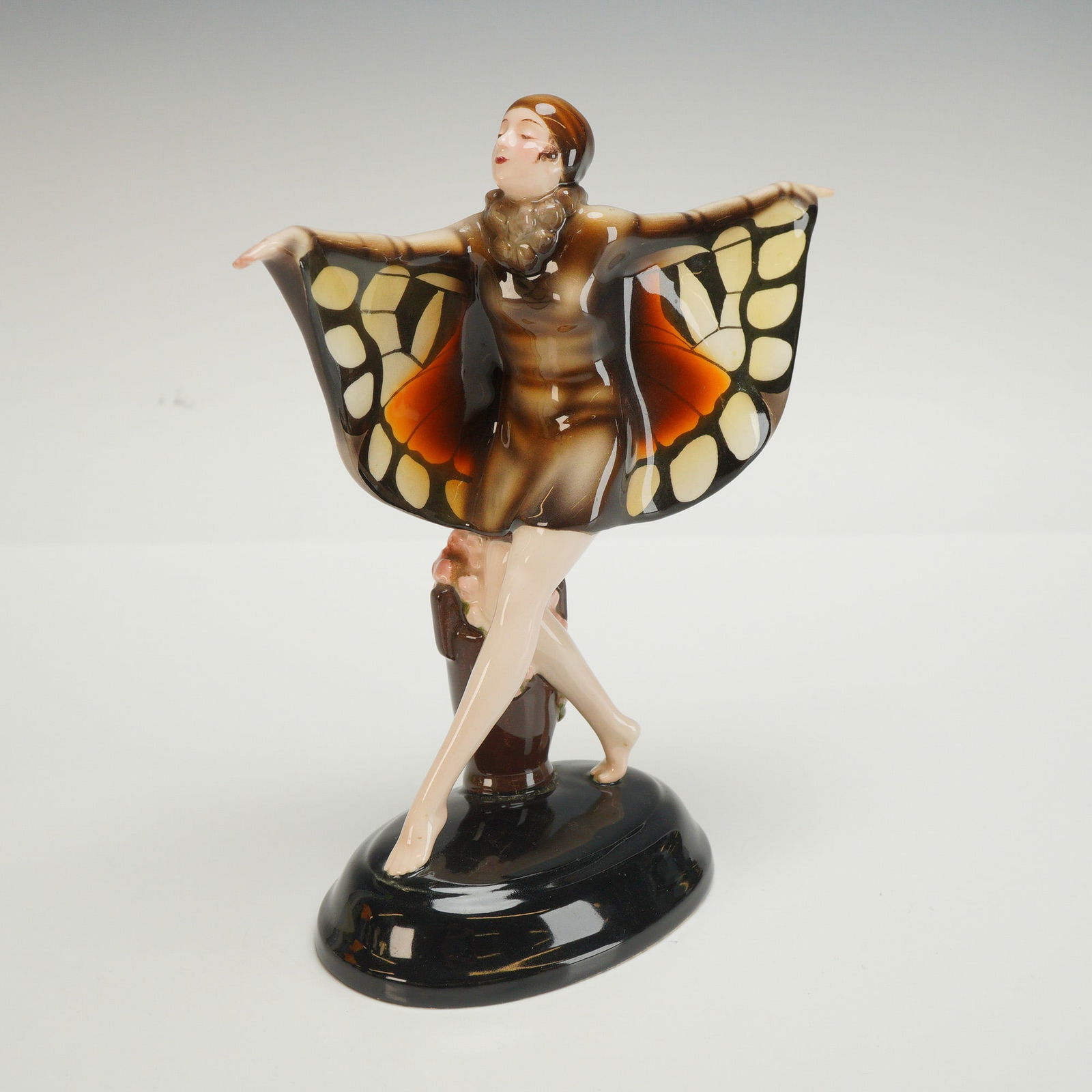 Goldscheider Josef Lorenzl Figurine, The Captured Bird: This glazed figure is modeled as a dancer with her hands outstretched, unveiling butterfly wings. It is hand painted in shades of brown, beige, and orange. The base is marked with model number 6600,