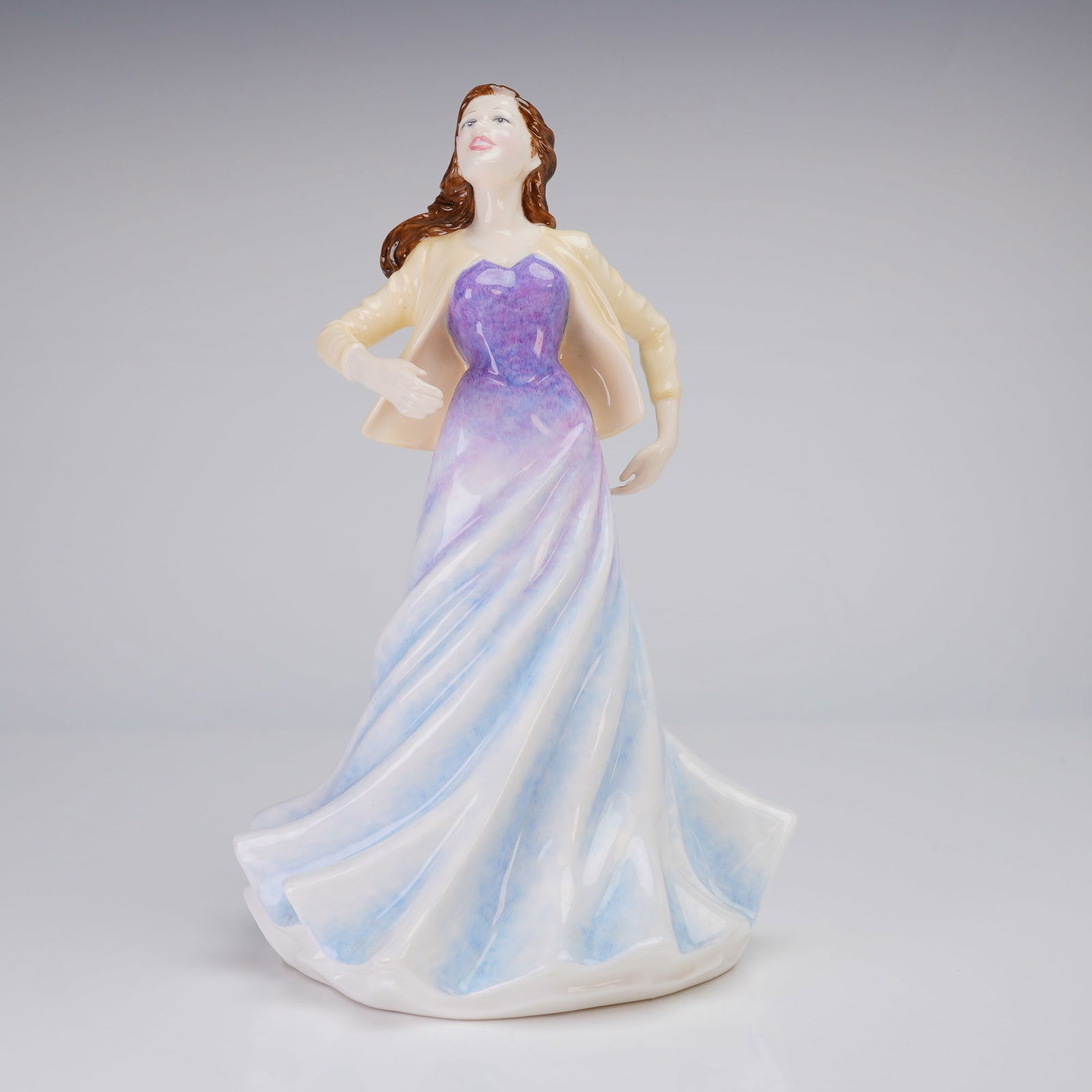 Royal Doulton Figurine, Suzanne Pilot Prototype: A single Royal Doulton porcelain figurine, Suzanna Pilot Prototype, depicting a woman with brown hair wearing a yellow jacket and a flowing purple, white, and light blue dress, marked "E SUZANNE