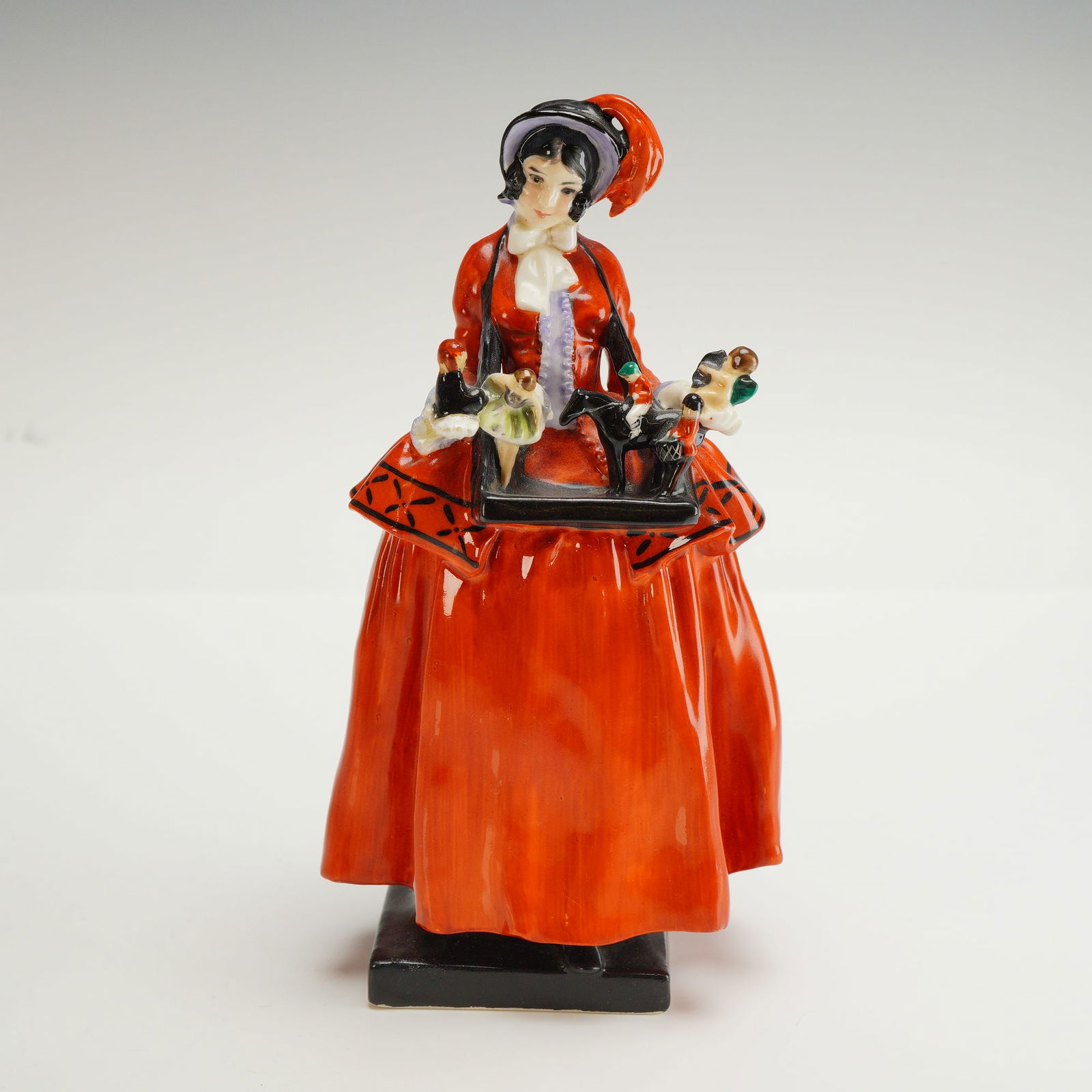 Royal Doulton Figurine, Sketch Girl Model 444: A hand painted figural model depicting a woman in a red-orange period dress and black bonnet, created for The Sketch magazine. The figure is based on the illustrated cover girl traditionally associate