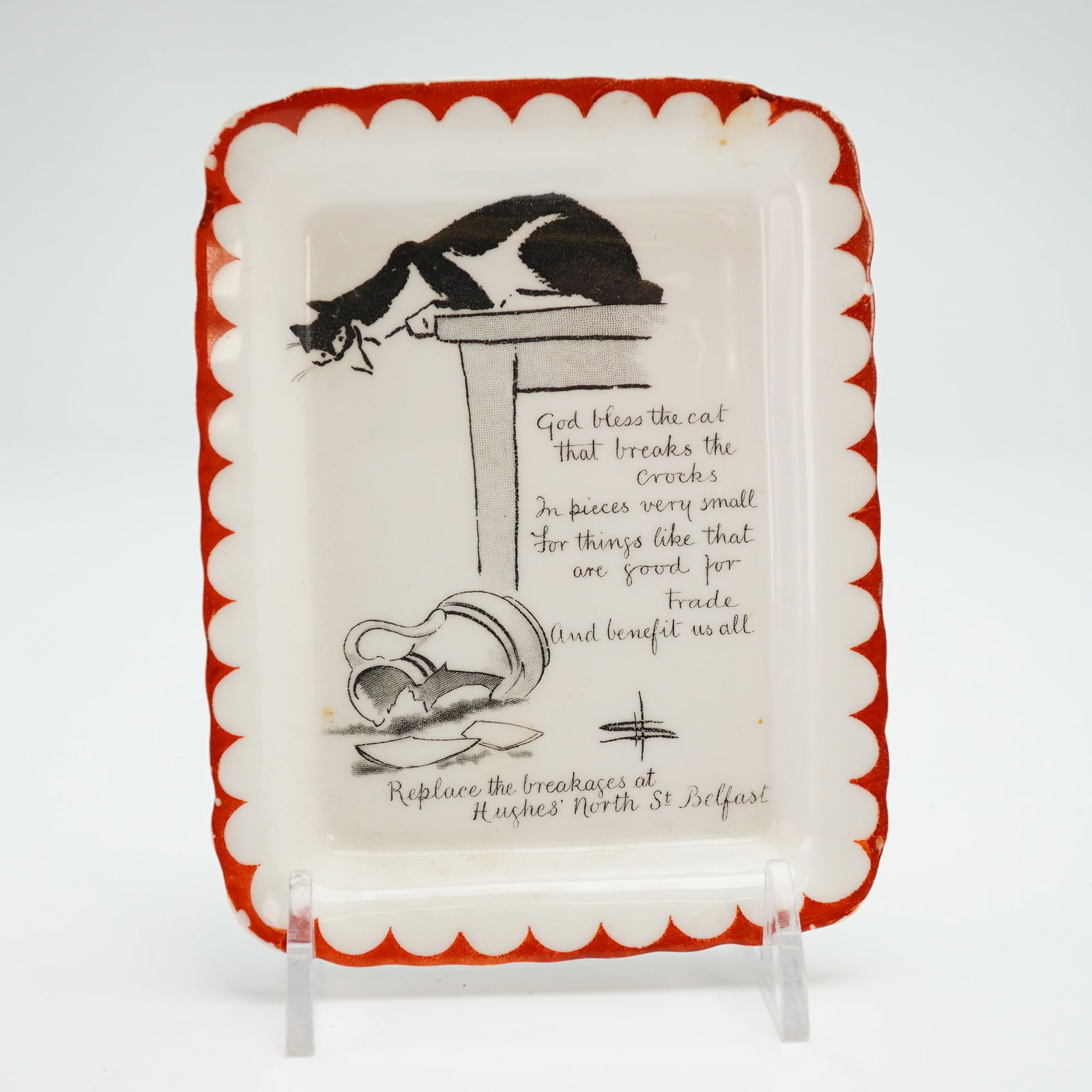 Royal Doulton by David Henry Souter Series Ware Dish, Kateroo: A white porcelain plate with a red rim, features a black and white cat on top of a table, peering down at the broken jug below. The inscription reads: God bless the cat that breaks the croooks in piec