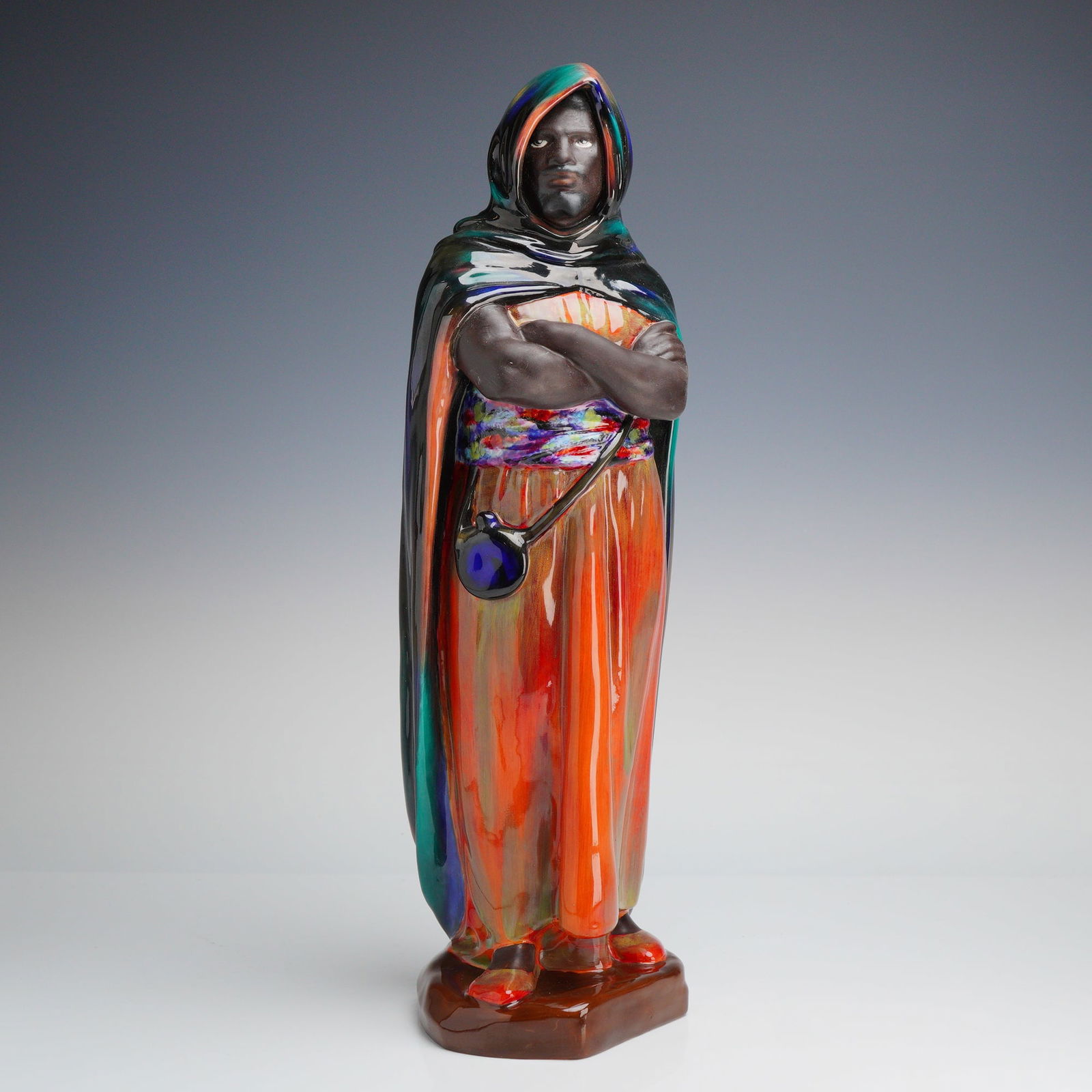 Royal Doulton Figurine The Moor HN2082: A highly glazed Royal Doulton Bone China Sculpture, model HN2082 The Moor, depicting a figure in a multi-color cloak, marked on the underside with the Royal Doulton backstamp and model name. Dimension
