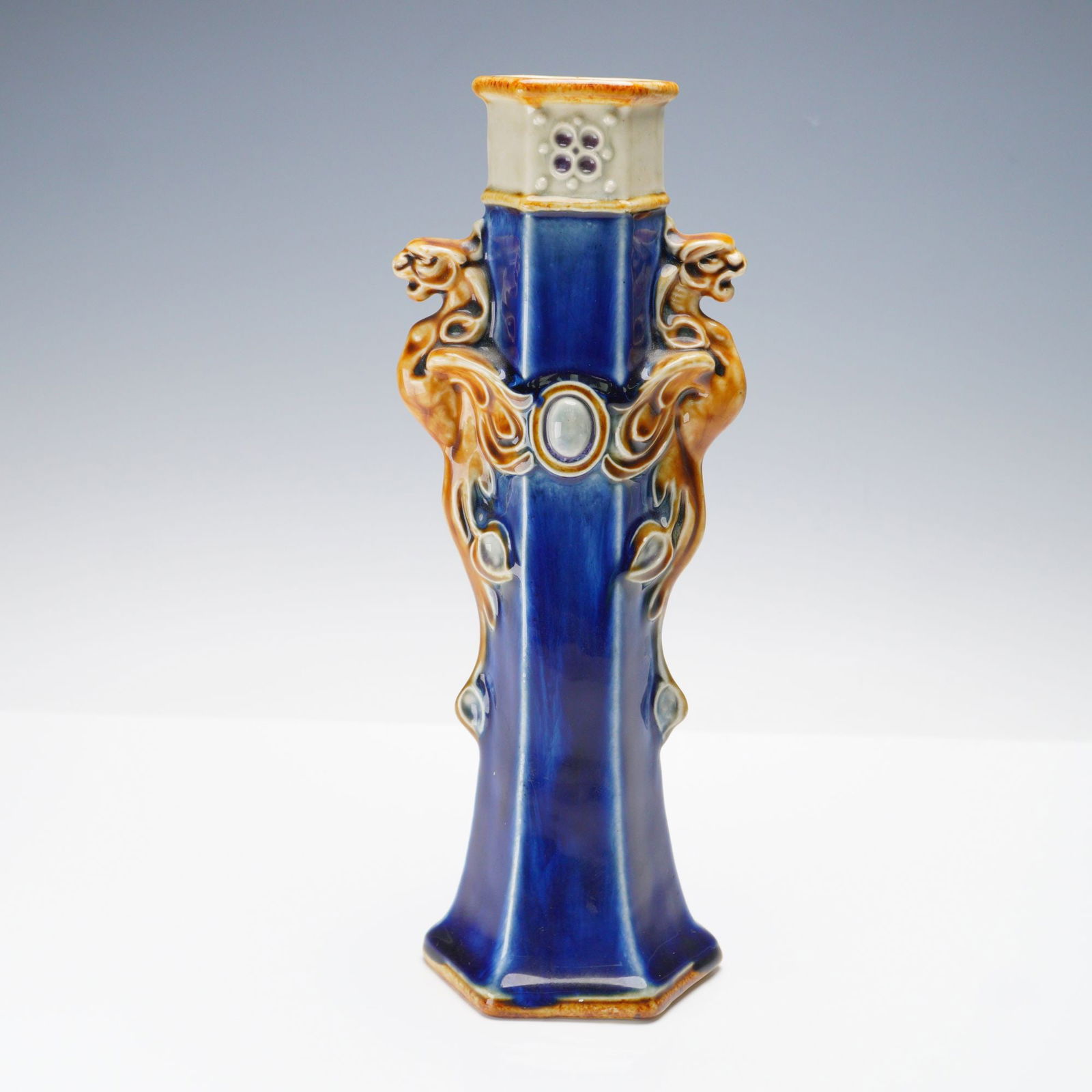 Doulton Lambeth by Francis C. Pope Stoneware Hexagonal Sleeve Vase: Stoneware hexagonal vessel of sleeve-form with applied high relief grotesque gargoyle handles on two opposing sides. Exhibits a cobalt blue body with brown and white coloration. F. C. P. incised to un