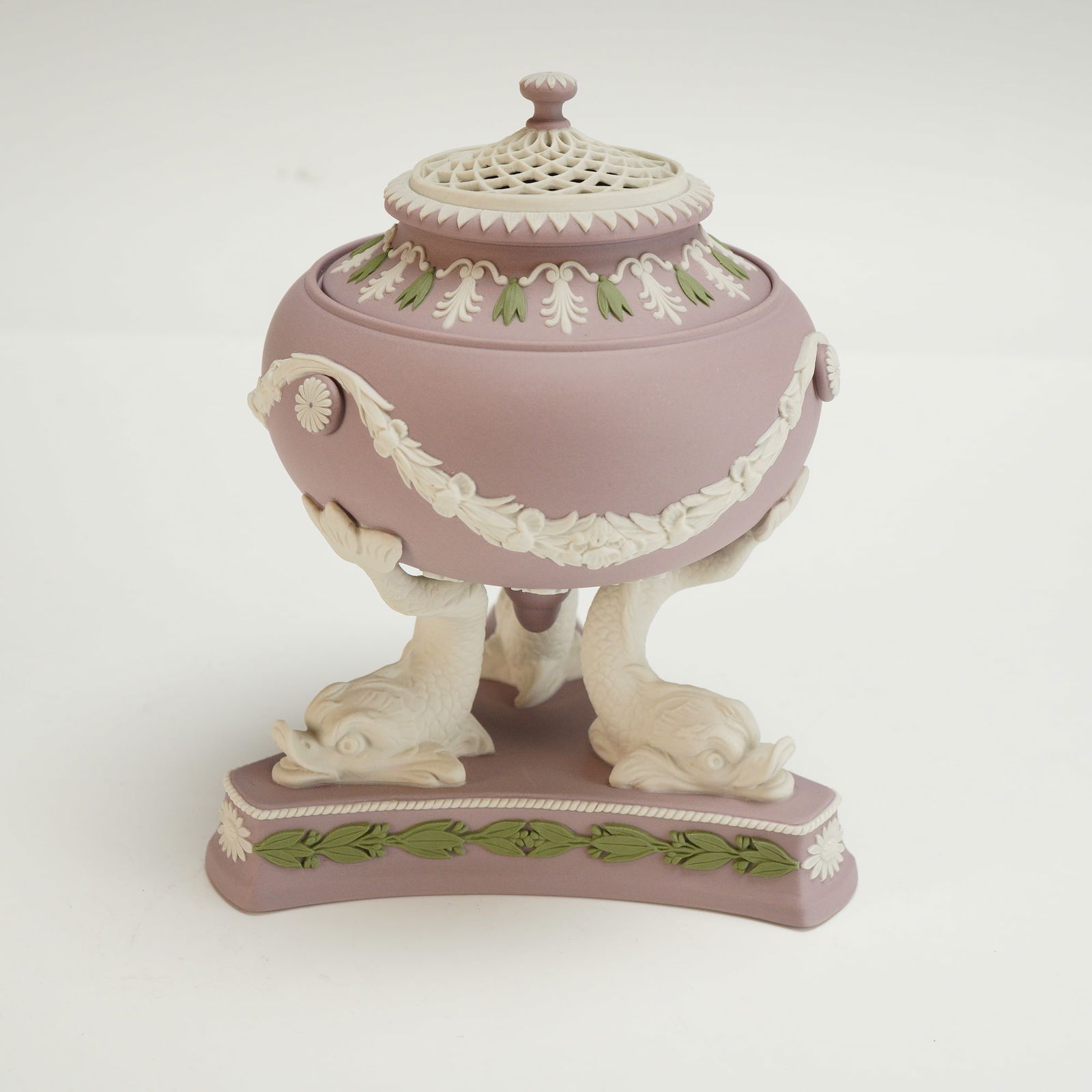Wedgwood Tricolor Jasperware Lidded Potpourri Vase: The vase is lilac purple and features a bowl supported on the tails of three molded white medieval dolphins on a triangular-form base. Garlands of white and sage green flowers and leaves decorate the