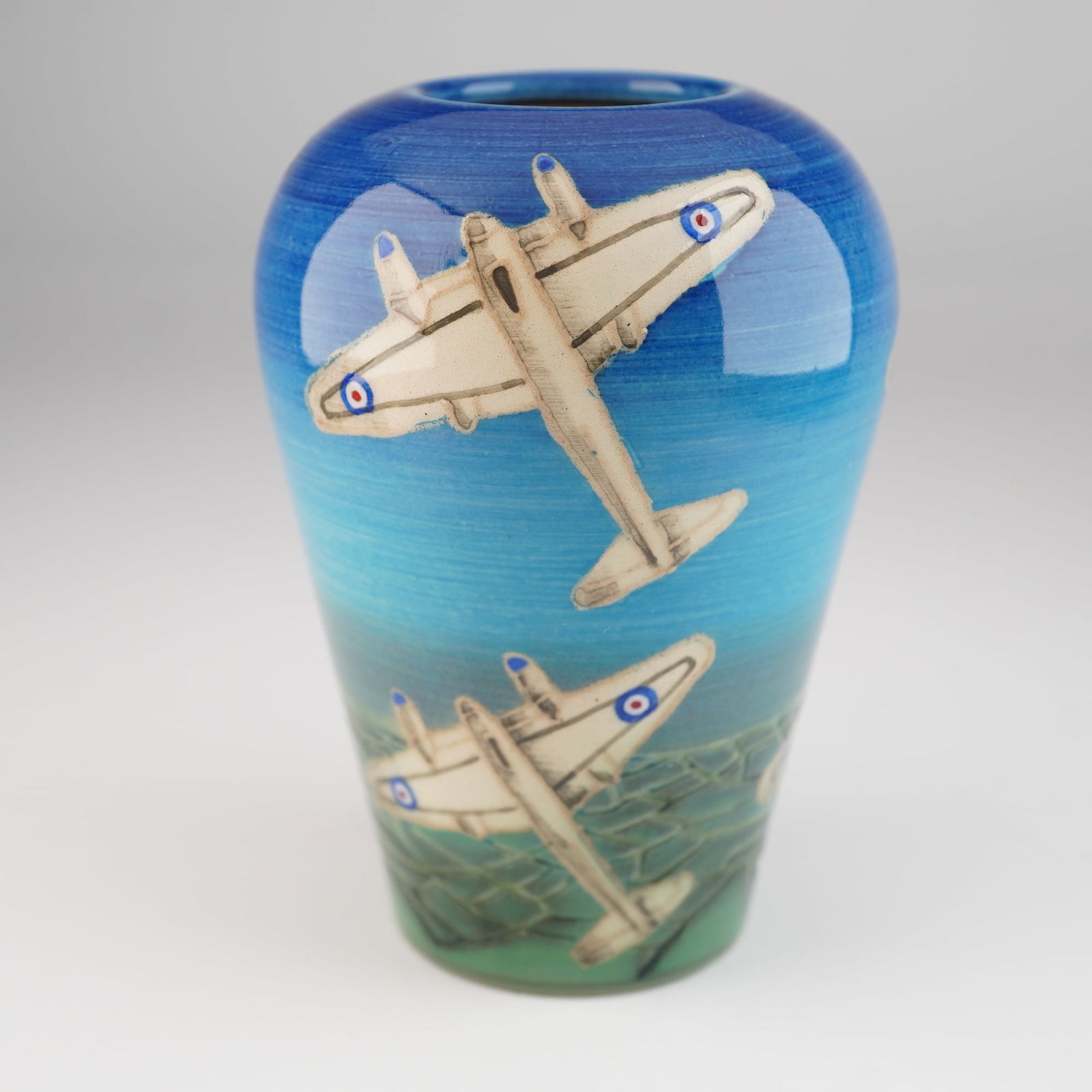 Dennis Chinaworks Sally Tuffin Airplanes Bud Vase Dated 2004: A single modern glazed ceramic bud vase produced by Dennis Chinaworks, designed by Sally Tuffin. The vase features an inverted baluster form with a high-gloss finish. The exterior decoration consists
