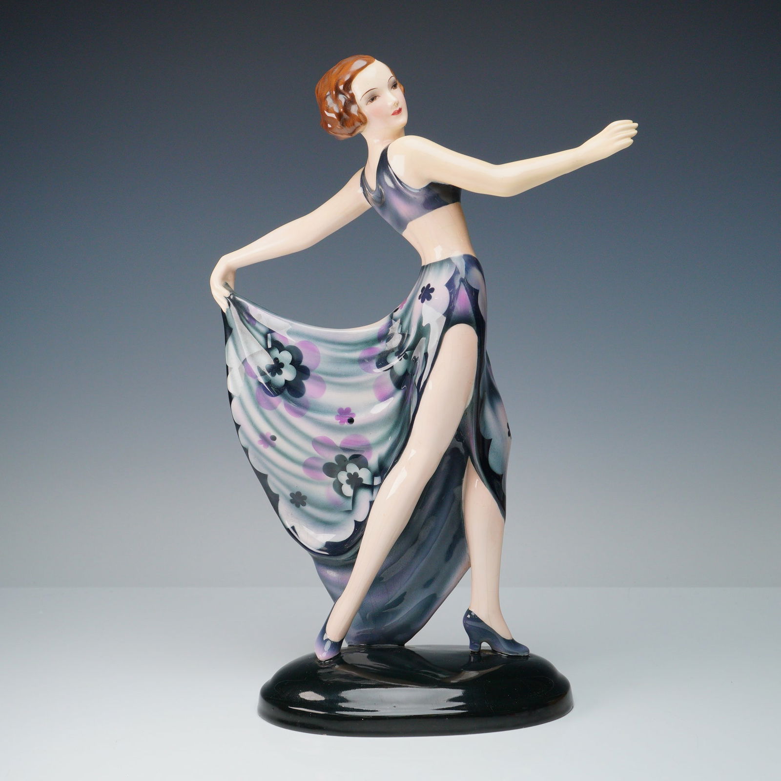 Goldscheider Art Deco Figurine, Dancer: Remarkable ceramic art deco modeled as a dancer embodying elegance and glamour. Features a poised dancer holding the end of her skirt in mid pose. Decorated in tones of pink with dark grey; stands on