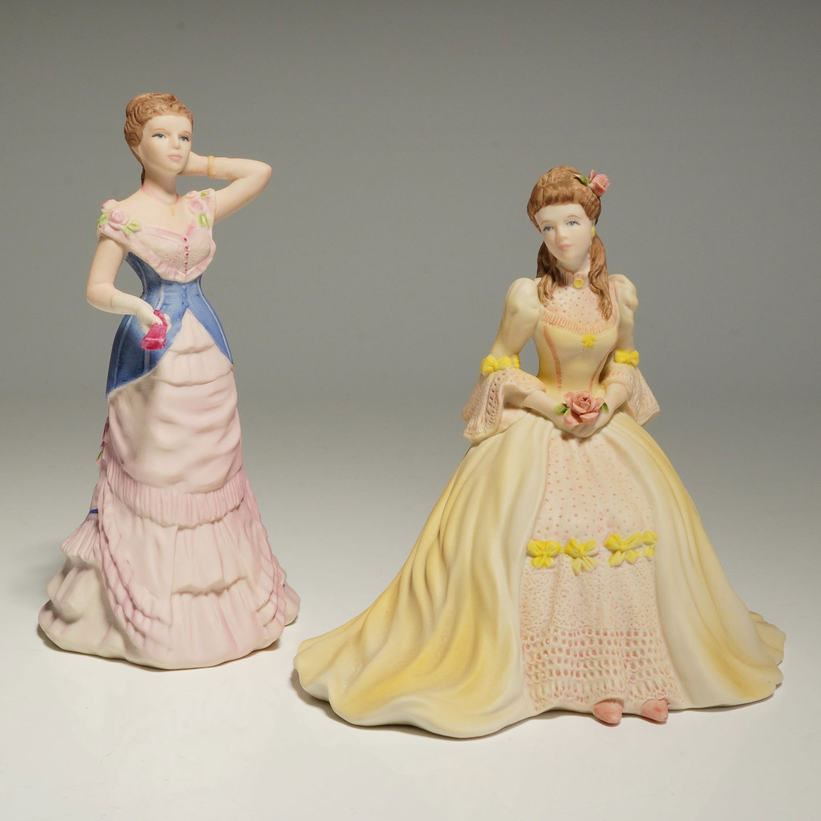 2pc Coalport Beau Monde Figurines, Kate and Georgina: A group of bisque porcelain figurines from the Beau Monde collection, featuring the models Georgina and Kate. Georgina is a standing figure modeled by Martin Evans, depicted in a Victorian-style gown