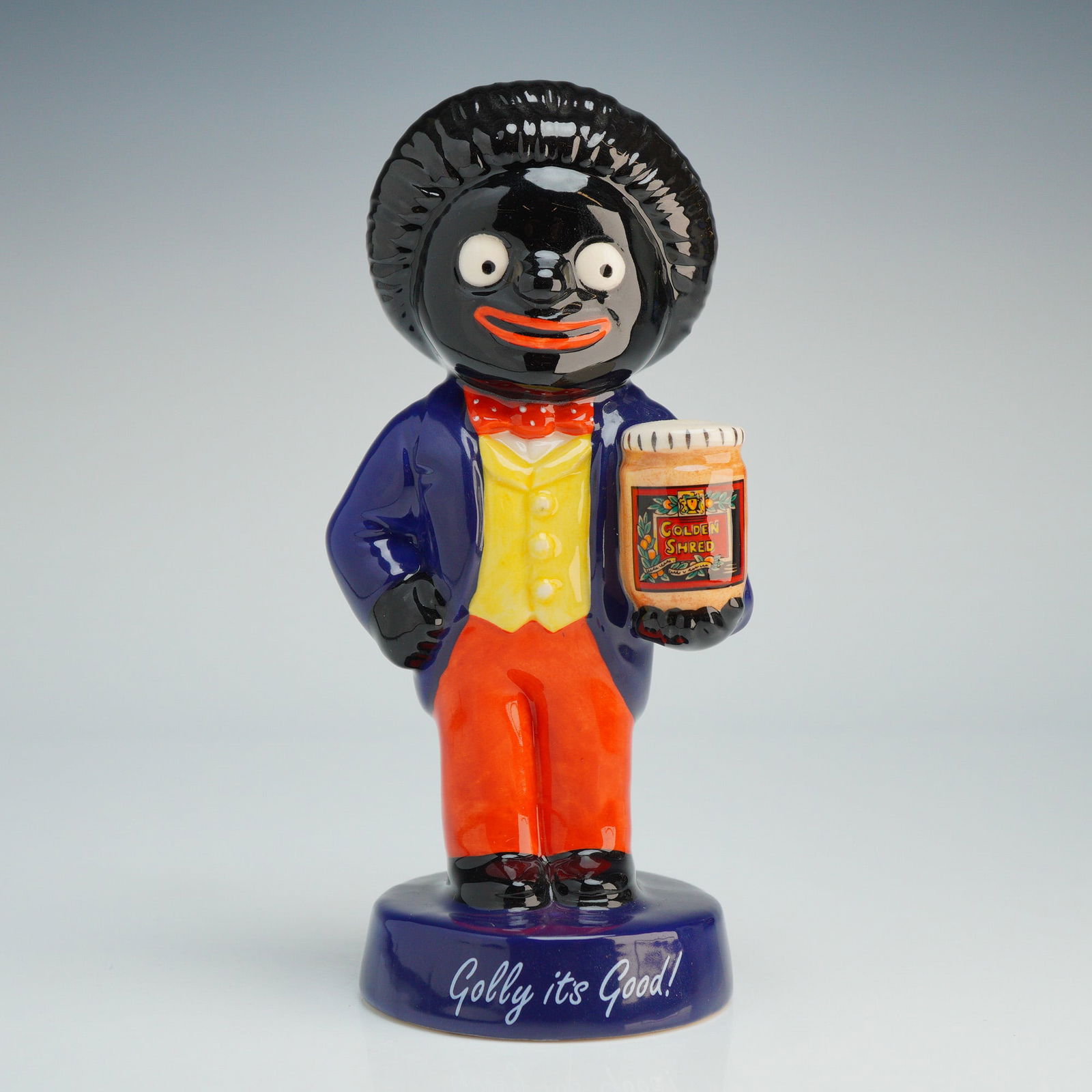 Royal Doulton 20th Century Advertising Figurine, Golly AC1: A glazed figurine from the 20th Century Advertising Classics series, depicting the James Robertson and Sons advertising character, Golly. The figure is modeled wearing a blue tailcoat, yellow waistcoa