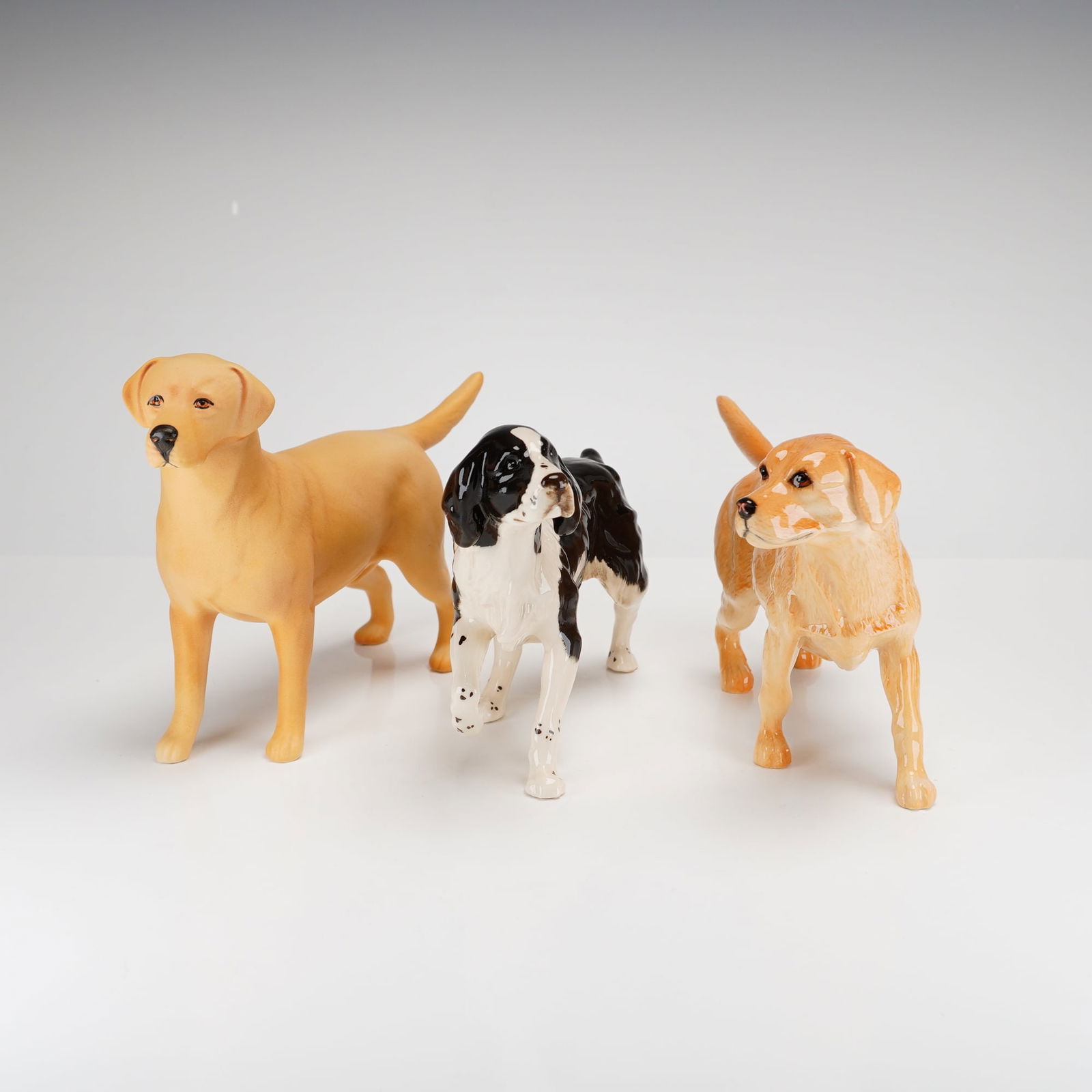 Three Beswick Ceramic Dog Figurines: This 3pc beswick dog figurines collection includes two Labrador Retrievers and one Springer Spaniel. One yellow Labrador is rendered in a matte finish and is marked Solomon of Wendover to the undersid