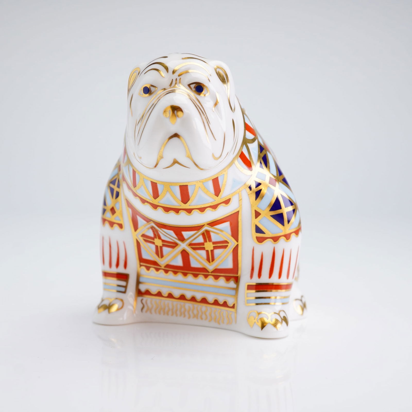 Royal Crown Derby Bulldog Paperweight: This Royal Crown Derby paperweight is modeled as a seated bulldog. The piece is constructed of fine bone china and features a traditional Imari-style palette of cobalt blue and iron red, accented with
