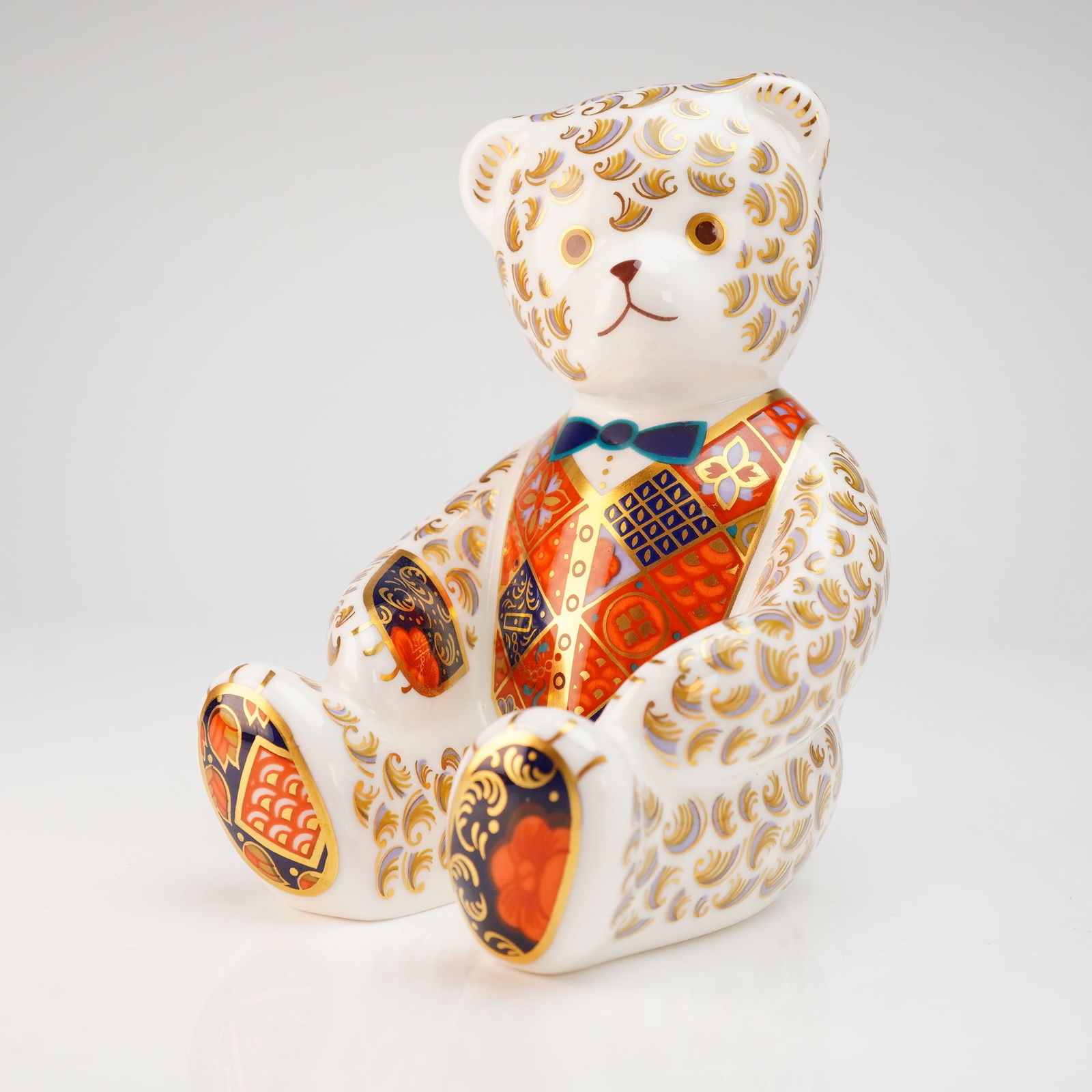 Royal Crown Derby Teddy Bear Paperweight: A Royal Crown Derby fine bone china paperweight depicting a seated teddy bear. The figure is decorated in an Imari-style palette featuring cobalt blue, iron red, and gilded accents. The bear is render