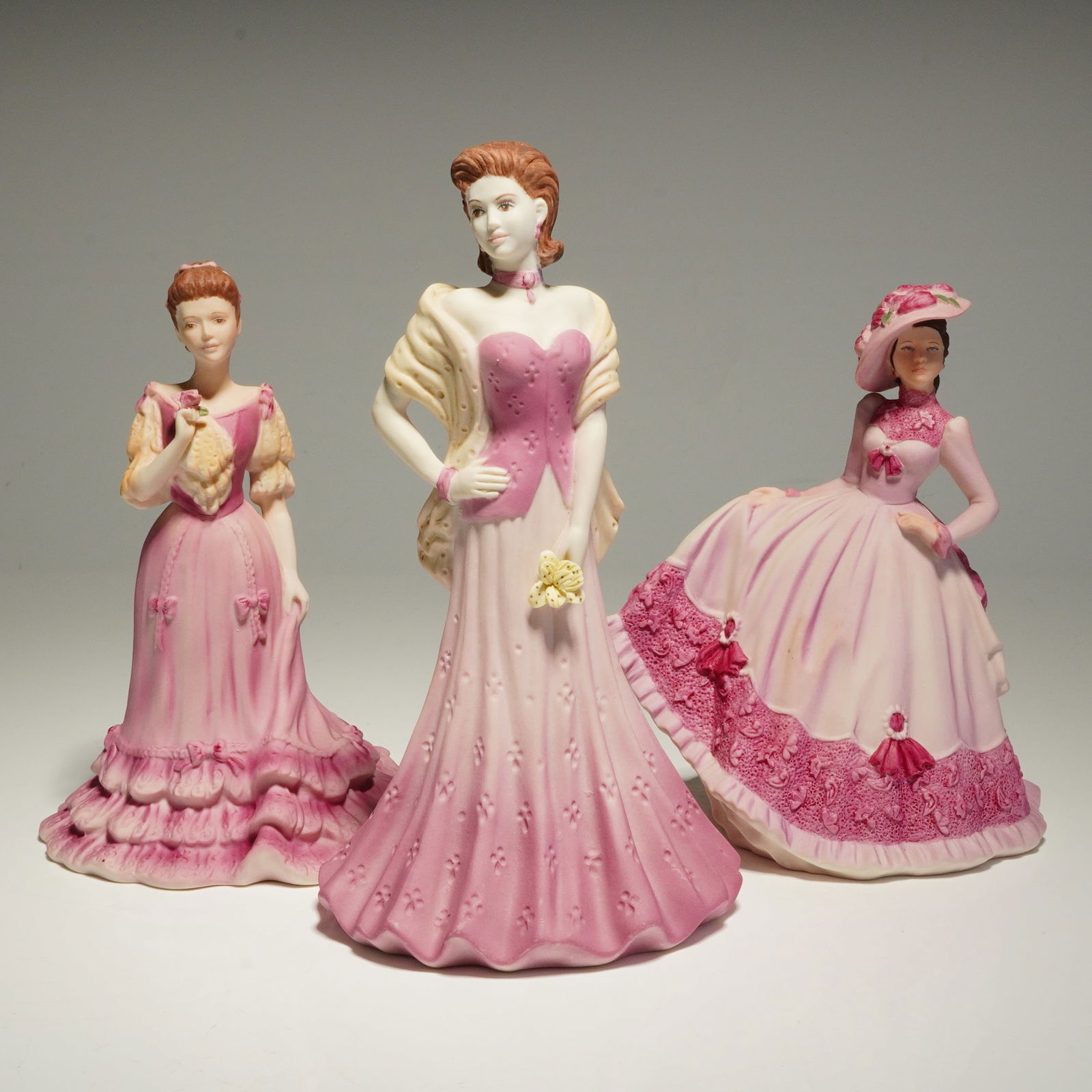 3pc Coalport Beau Monde Figurines, Sheila, Jill, and Isobel: A group of three Coalport hand-decorated bisque porcelain figurines from the Beau Monde series, including the models Sheila, Jill, and Isobel. Each figure is depicted in Edwardian-style attire featuri