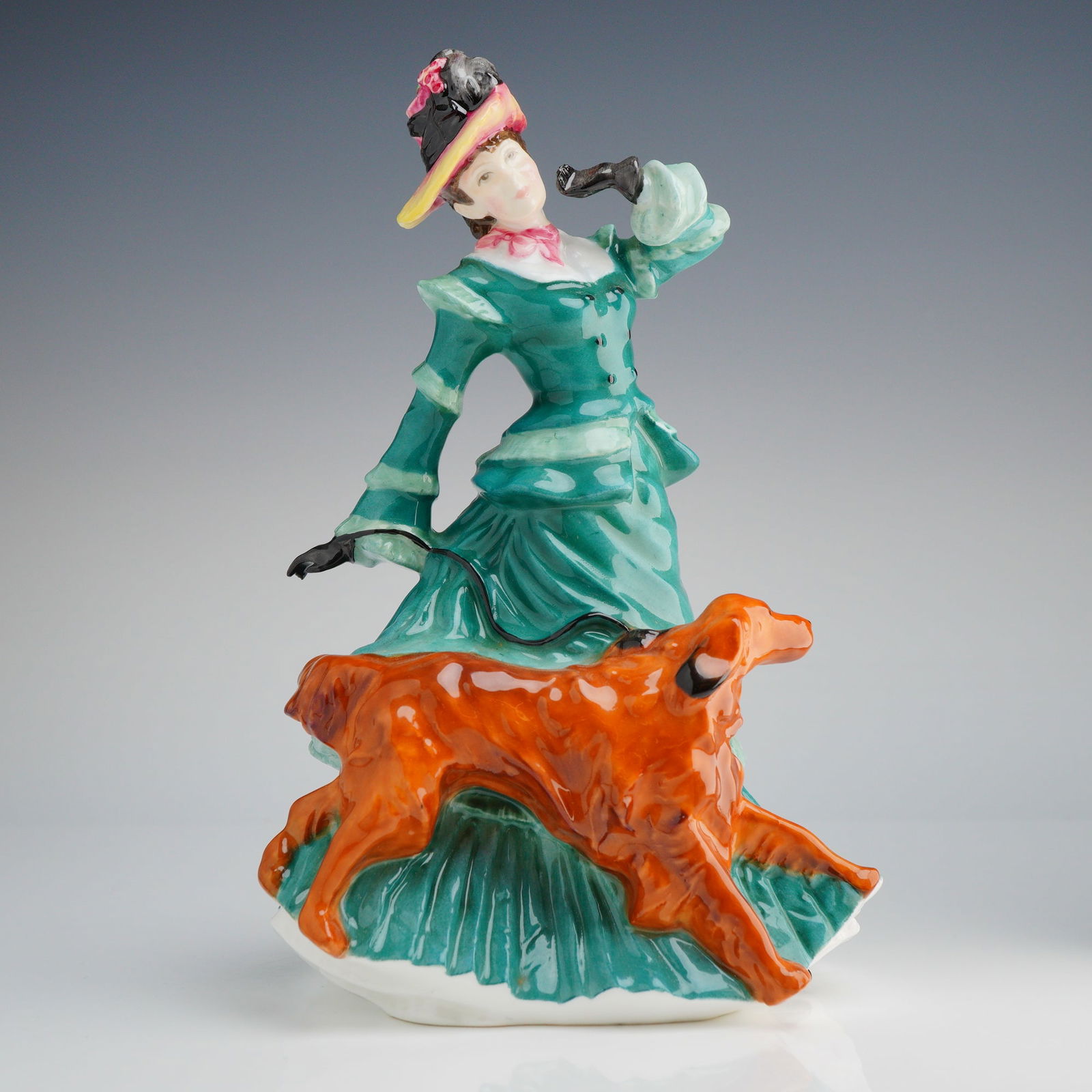 Royal Doulton Figurine, Autumntime HN3621: The piece depicts a woman in a vibrant teal and green period-style walking dress and ruffled hat, accompanying a reddish-orange dog, identified in market context as an Irish Setter, on a leash. The fi