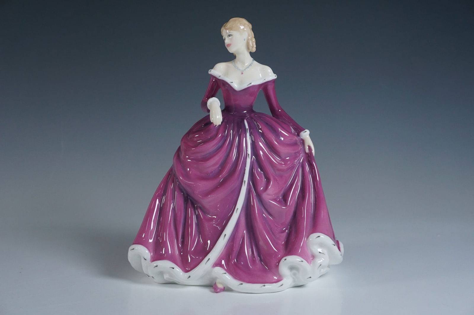 Royal Doulton Figurine, Belle HN4235: This exquisite bone china figurine is part of the esteemed Royal Doulton Classics collection. It features a beautifully detailed design, showcasing a lady in a flowing purple gown with intricate accen