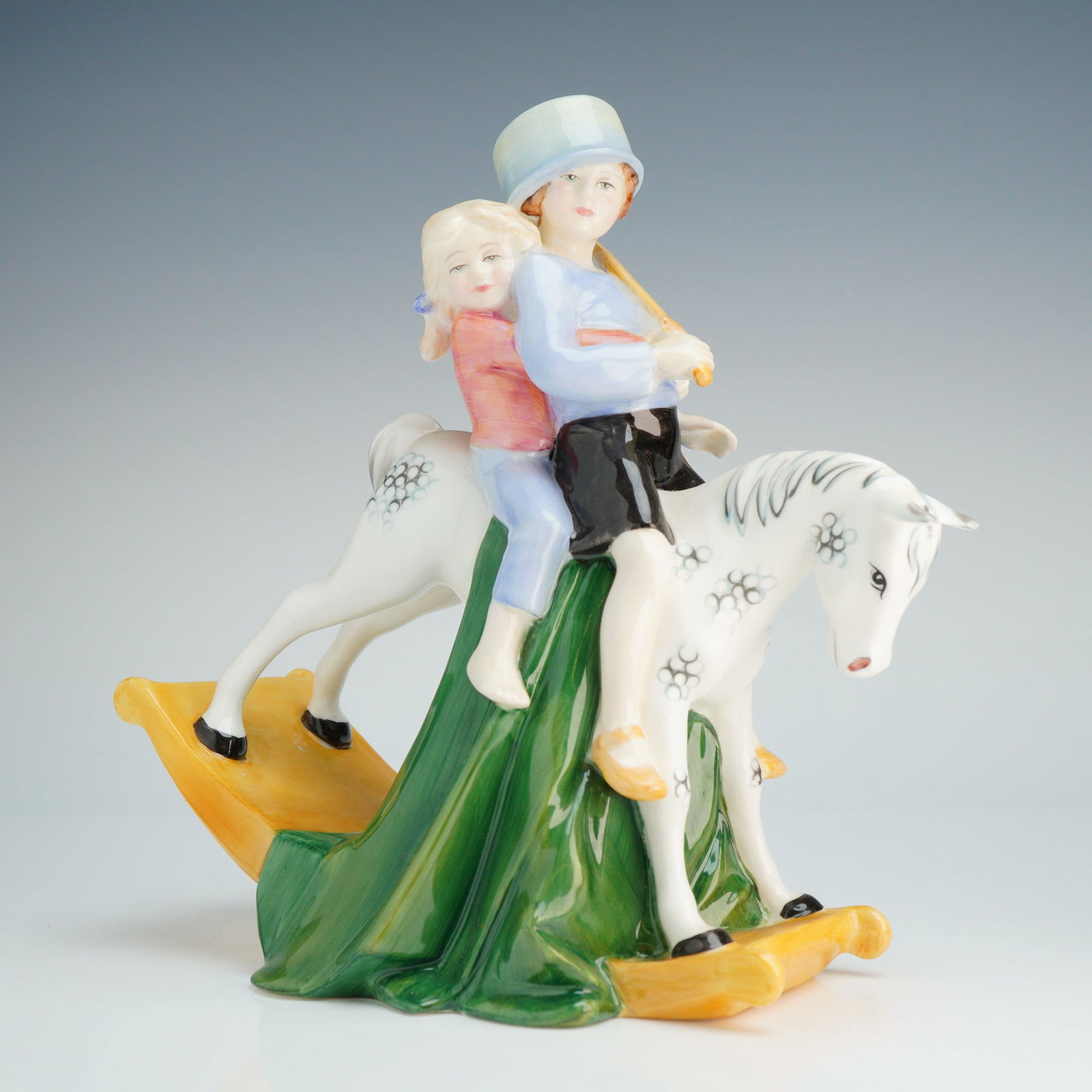 Royal Doulton Figurine Hold Tight HN3298: This piece was modeled by Adrian Hughes and is dated 1990. The figurine is hand-made and hand-decorated with a glossy glaze finish. The composition depicts two children riding a white dapple-gray rock