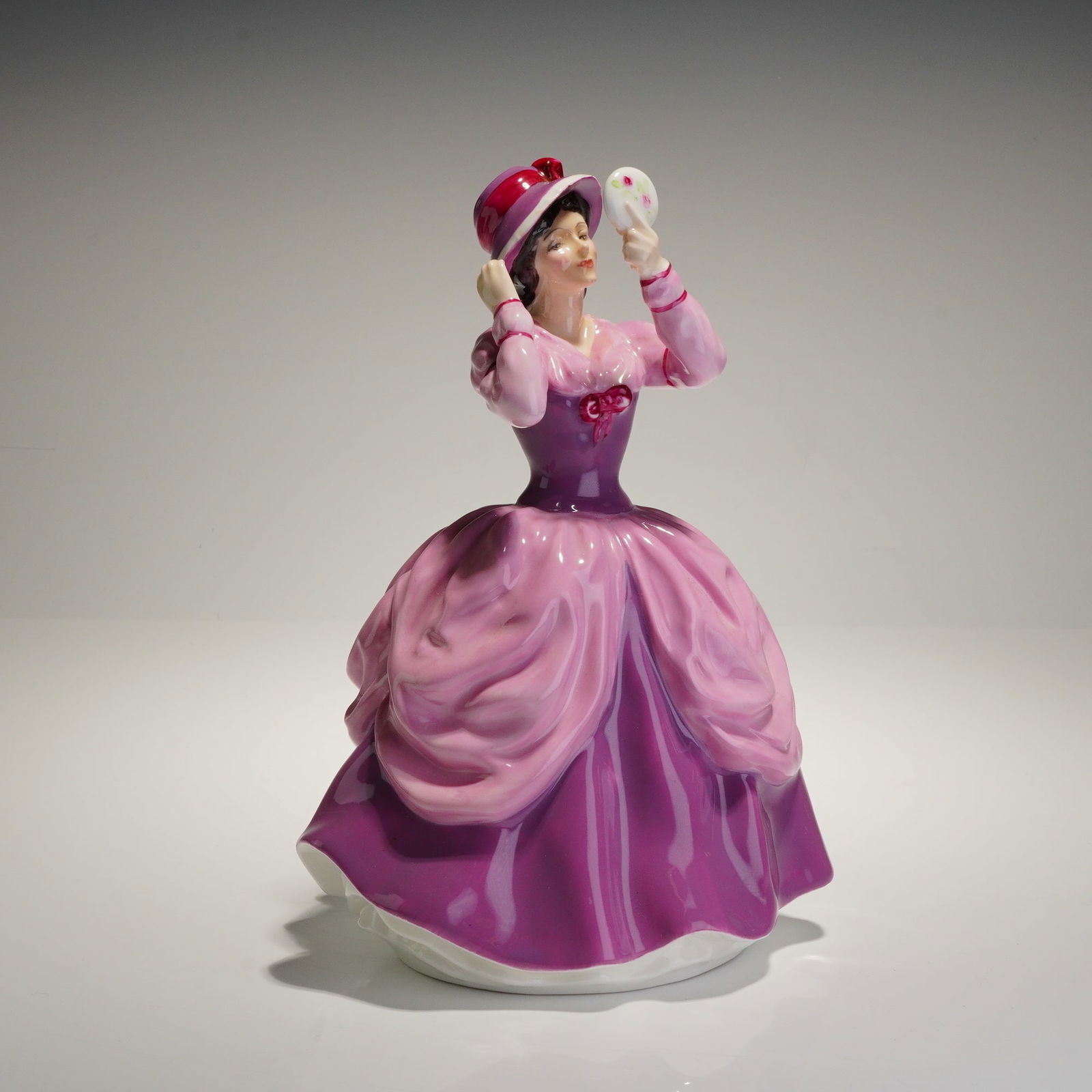 Royal Doulton Figurine Lady Pamela HN2718: A glazed bone china figurine manufactured by Royal Doulton, titled the "Lady Pamela," model number HN 2718. The figure depicts a lady in a voluminous period gown and wide-brimmed hat, rendered primari