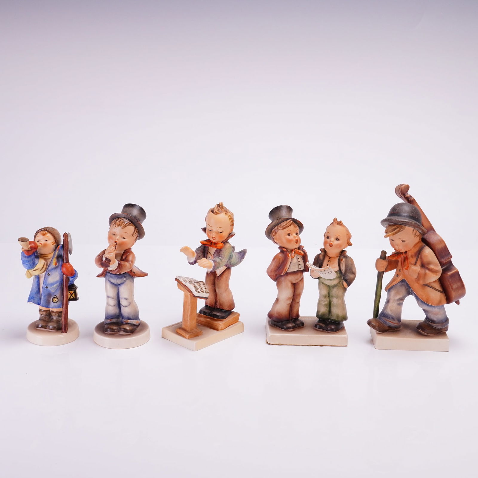 5pc Goebel Hummel Figurines, Singers and Musicians: Hand-painted porcelain figures depicting children in various musical and town-crying roles. The group includes a night watchman titled Hear Ye, Hear Ye, a boy playing a flute, a Band Leader with a
