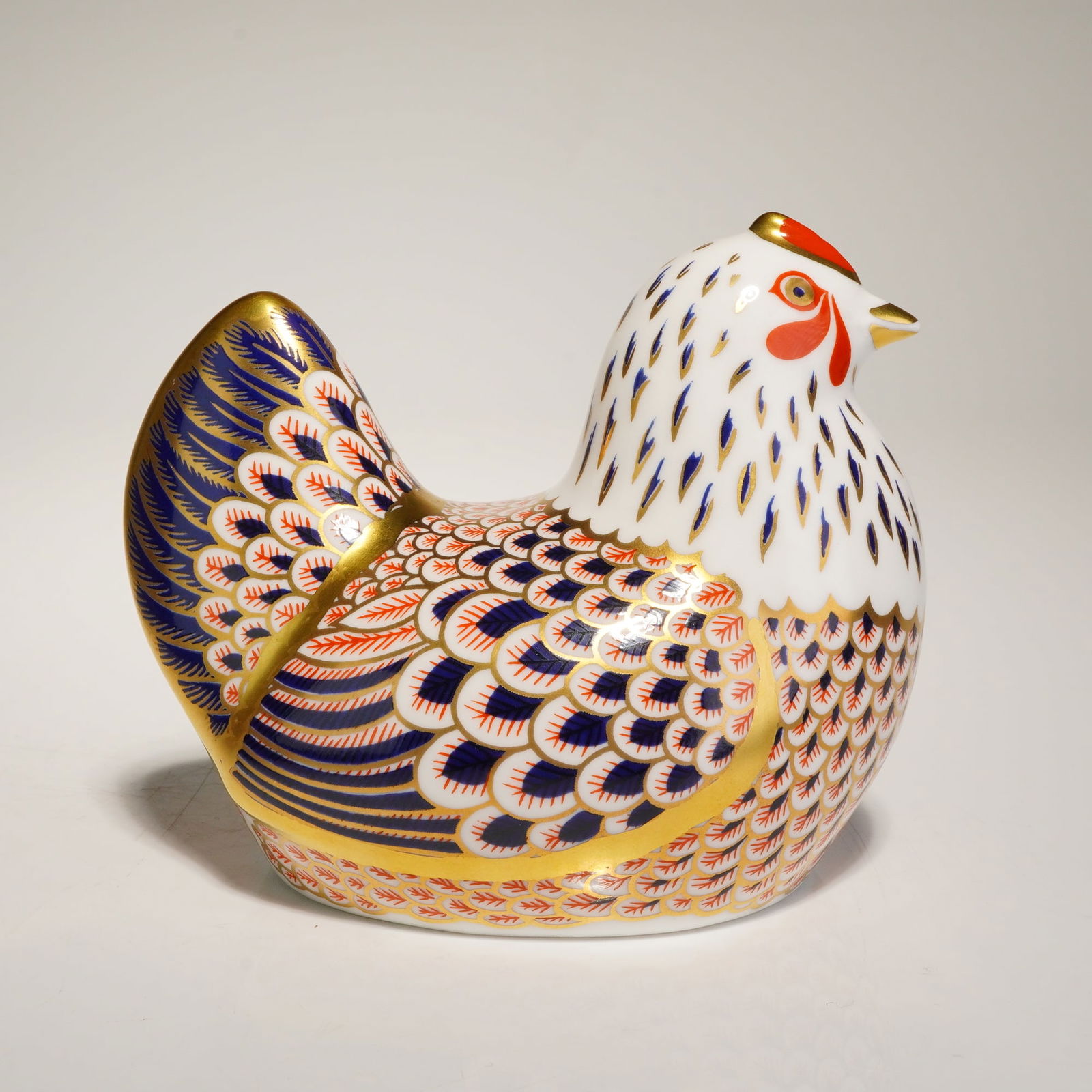 Royal Crown Derby Hen Paperweight: Royal Crown Derby hen paperweight composed of English bone china. The piece is decorated in a traditional Imari-style pattern with cobalt blue, iron red, and gold gilding. The decoration consists of