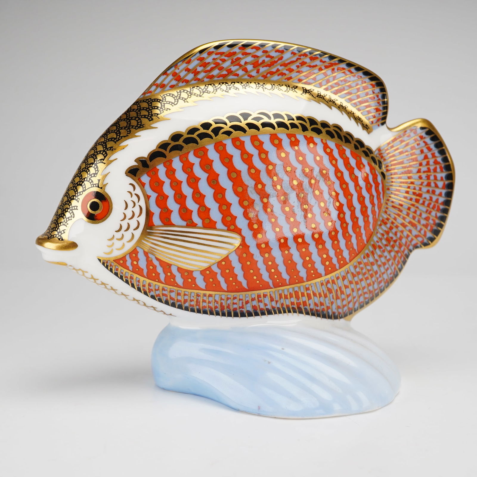 Royal Crown Derby Paperweight, Tropical Fish Gourami: A Royal Crown Derby paperweight is from the Tropical Fish series. The figurine is modeled as a tropical fish resting on a pale blue stylized wave-form base. The decoration features an Imari-style