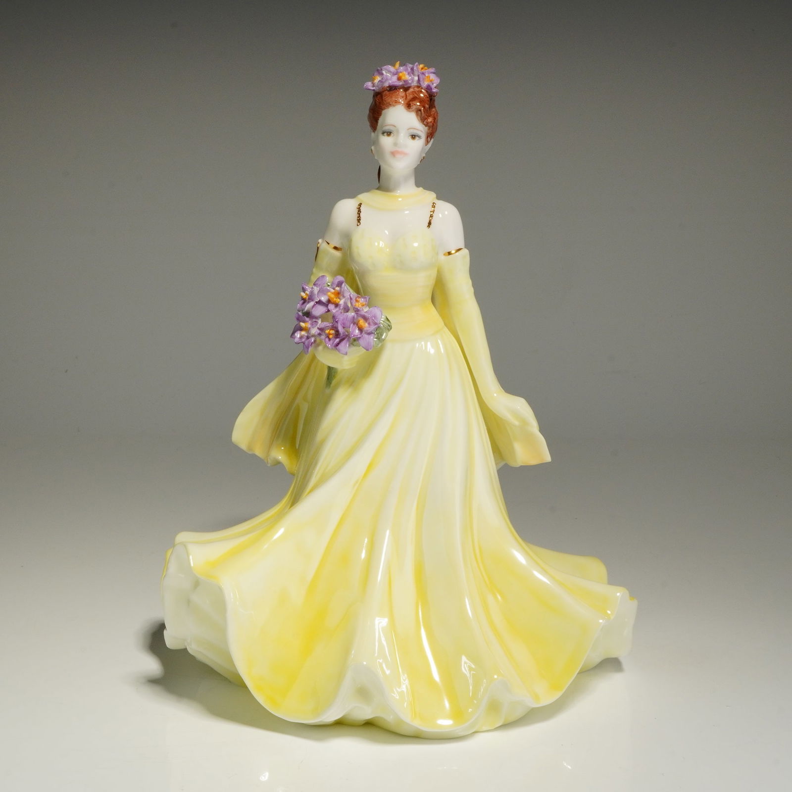 Coalport Bone China The Flower Ladies Collection Figurine, Dearest Iris: This hand-decorated figure depicts a woman with red hair wearing a pale yellow sleeveless gown and matching back stole. She is shown holding a bouquet of purple irises with a matching floral