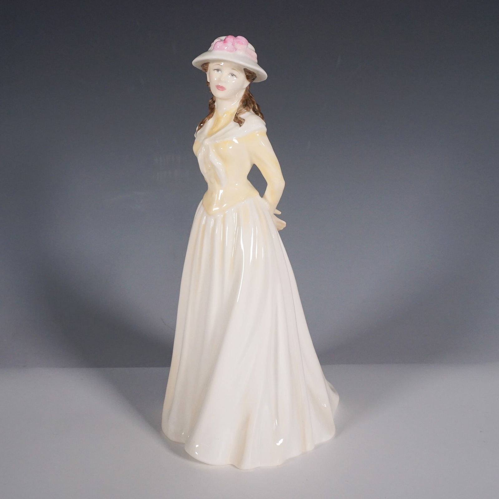 Royal Doulton Classics Figurine, Summer Stroll HN4406: Elegant Royal Doulton figurine part of the Classic Pretty Ladies series. This collectible figurine features a graceful woman in a flowing cream-colored gown with a fitted bodice, complemented by a