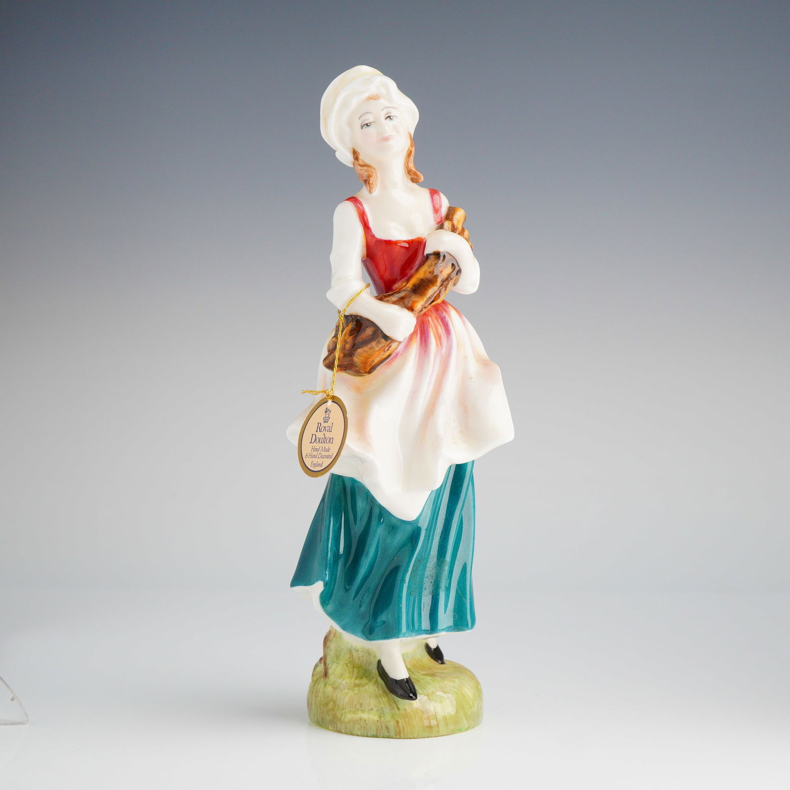 Royal Doulton Figurine, Lizzie HN 2749: A Royal Doulton figurine, modeled by Douglas V. Tootle in 1987, depicting a woman in a white, red, and teal dress holding bread, marked underneath. Royal Doulton backstamp on base. Dimensions: 8.50"H