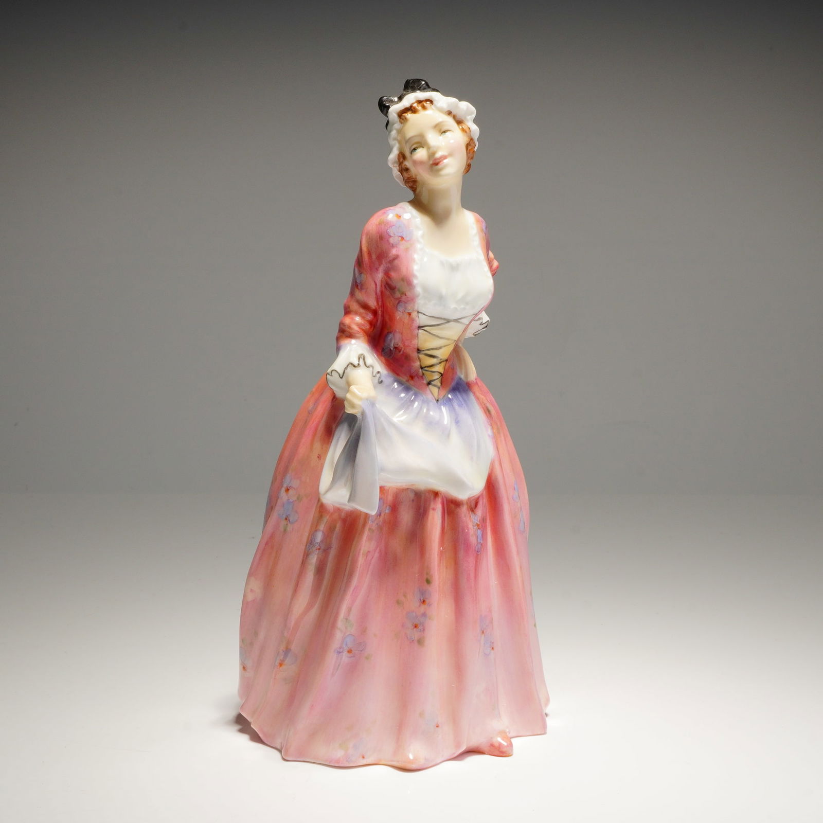 Royal Doulton Figurine Mary Jane HN1990: A Royal Doulton porcelain figurine, "Mary Jane" HN1990, depicting a woman in a pink and white dress, marked COPR. 1946 on the base. Dimensions: 3.75"L x 3.75"W x 7.75"H Weight: 13.00oz