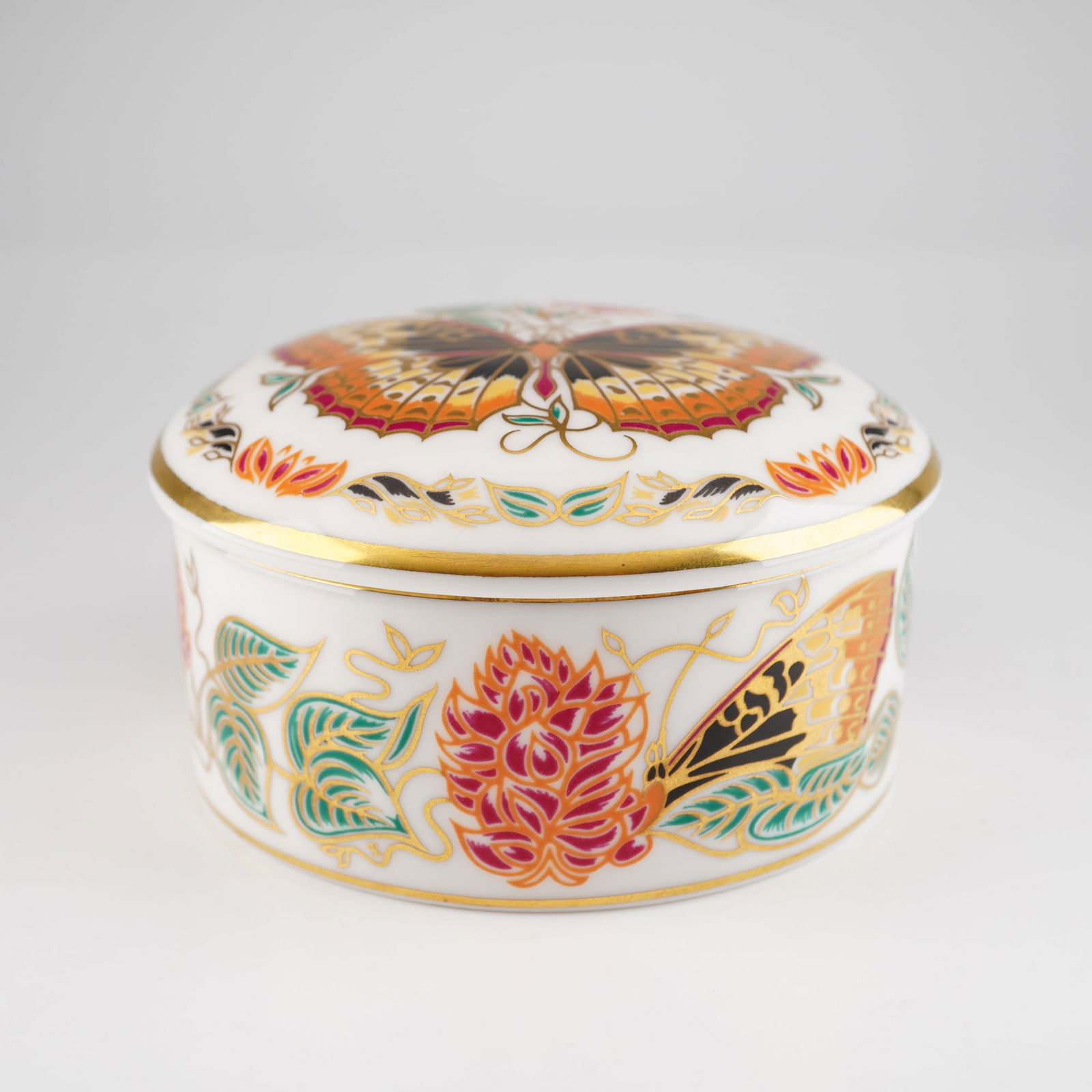 Royal Crown Derby Bone China Lidded Ring Box, Great Spangled Fritillary: A Royal Crown Derby English bone china circular lidded ring box from the Butterflies of the World series. The lid features a central polychrome illustration of a Great Spangled Fritillary butterfly se