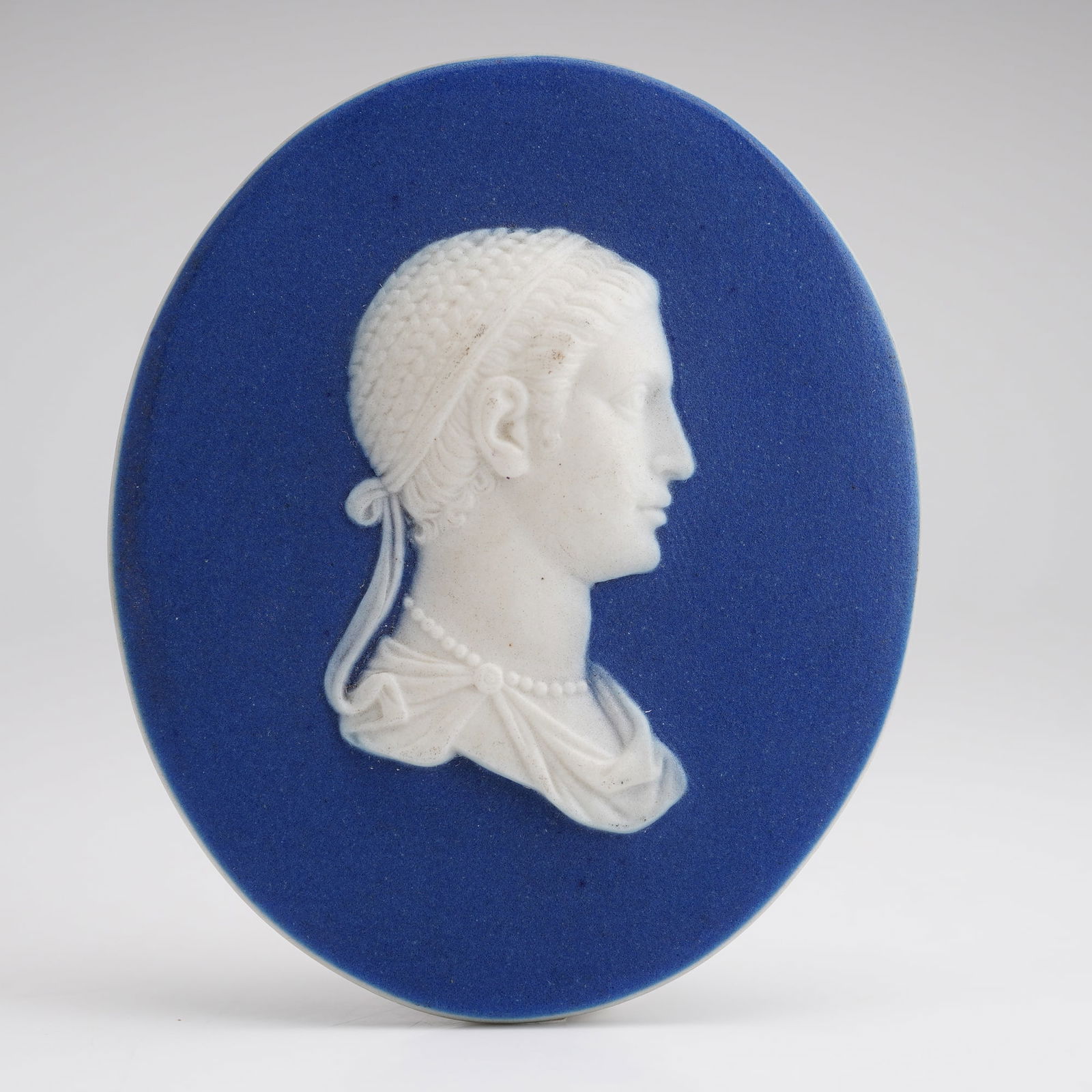 Wedgwood Blue and White Jasperware Oval Plaque of Cleopatra: A small oval blue and white Jasperware portrait plaque depicting Cleopatra facing right. The reverse side impressed with the "Wedgwood" stamp. Also marked "Cleopatra." Dimensions2.25"L x 2.00"W x 0.25