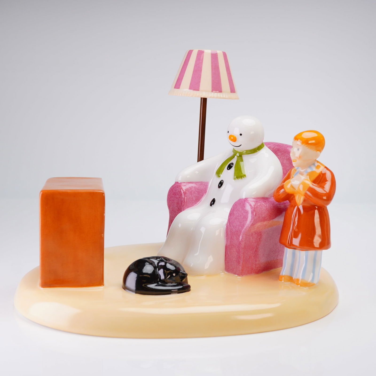 Coalport The Snowman Figurine, A Cold Night In: This limited edition, 398 of 500, hand-painted bone china figurine depicts the Snowman seated in a pink armchair, watching television alongside the young boy, with a black cat sleeping on the base. Th