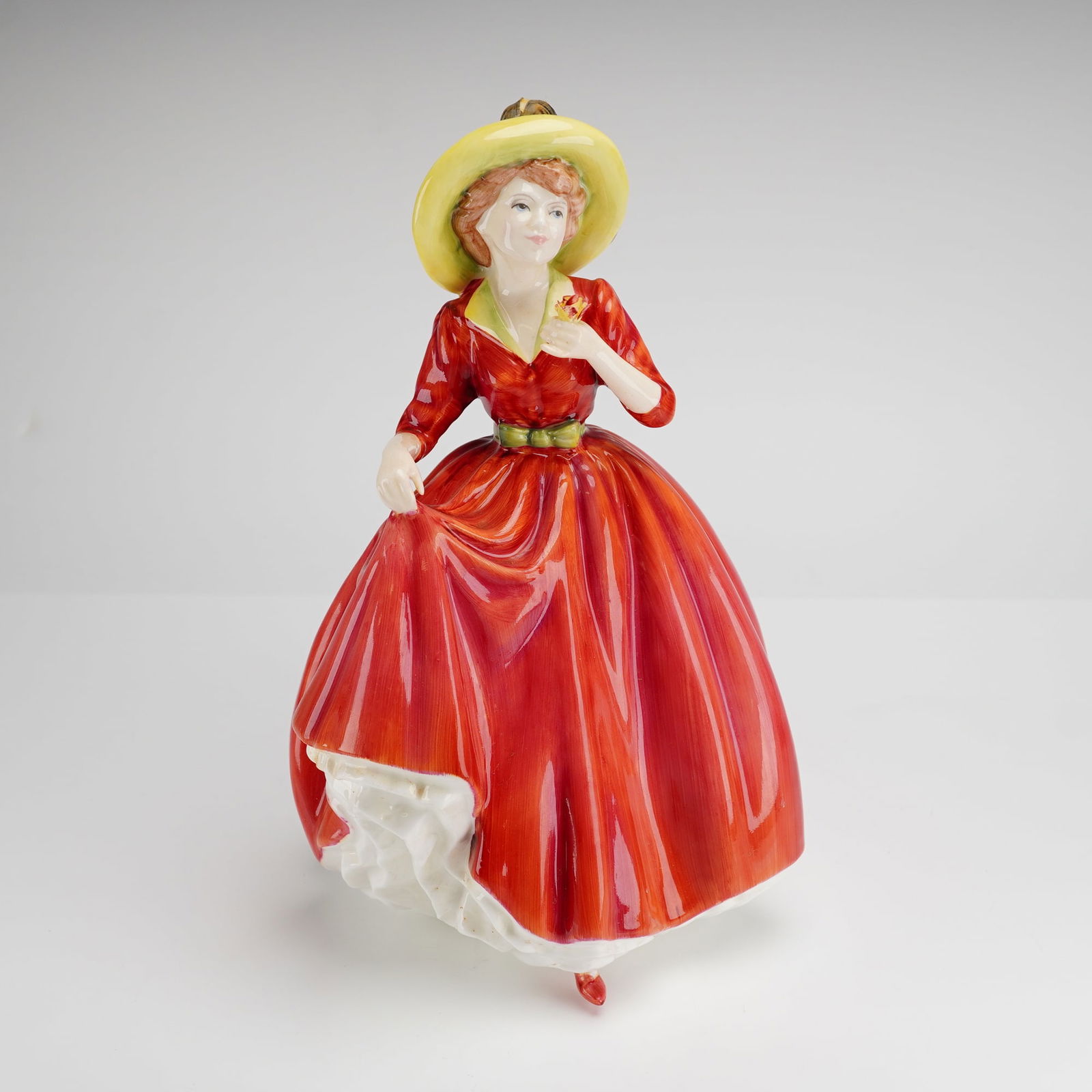 Royal Doulton A Single Red Rose Figurine HN3376: A Royal Doulton hand-decorated bone china figurine titled A Single Red Rose, model number HN 3376. The figure depicts a woman in a red gown with a green waistband and a yellow wide-brimmed hat accente