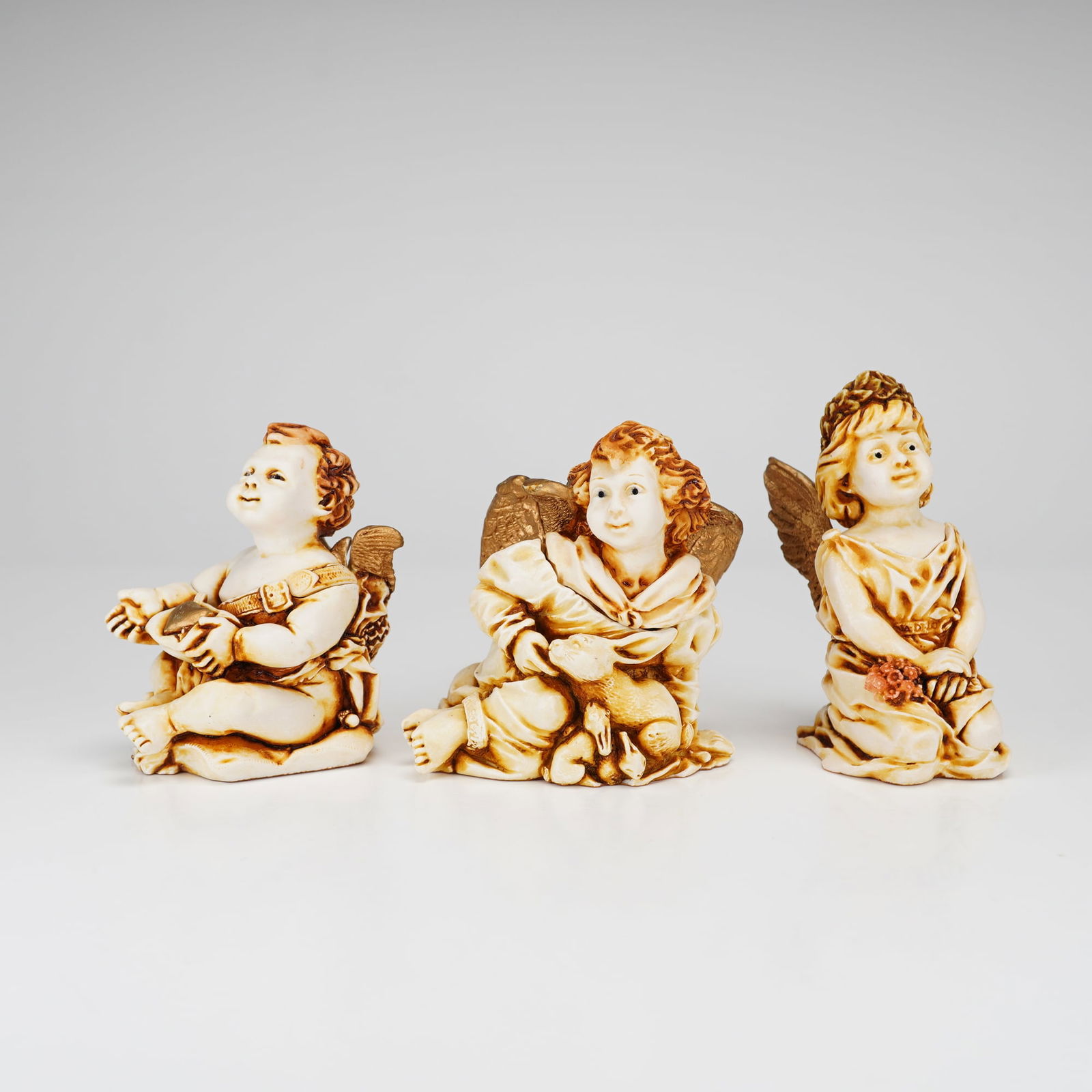 3pc Harmony Kingdom Boxes: Gentil Homme, Fleur De Lis, and Joie De Vivre: A trio of Harmony Kingdom cherub and angel-themed jewelry boxes, including the specific designs Gentil Homme, Fleur De Lis, and Joie De Vivre. These pieces are constructed from crushed marble and resi