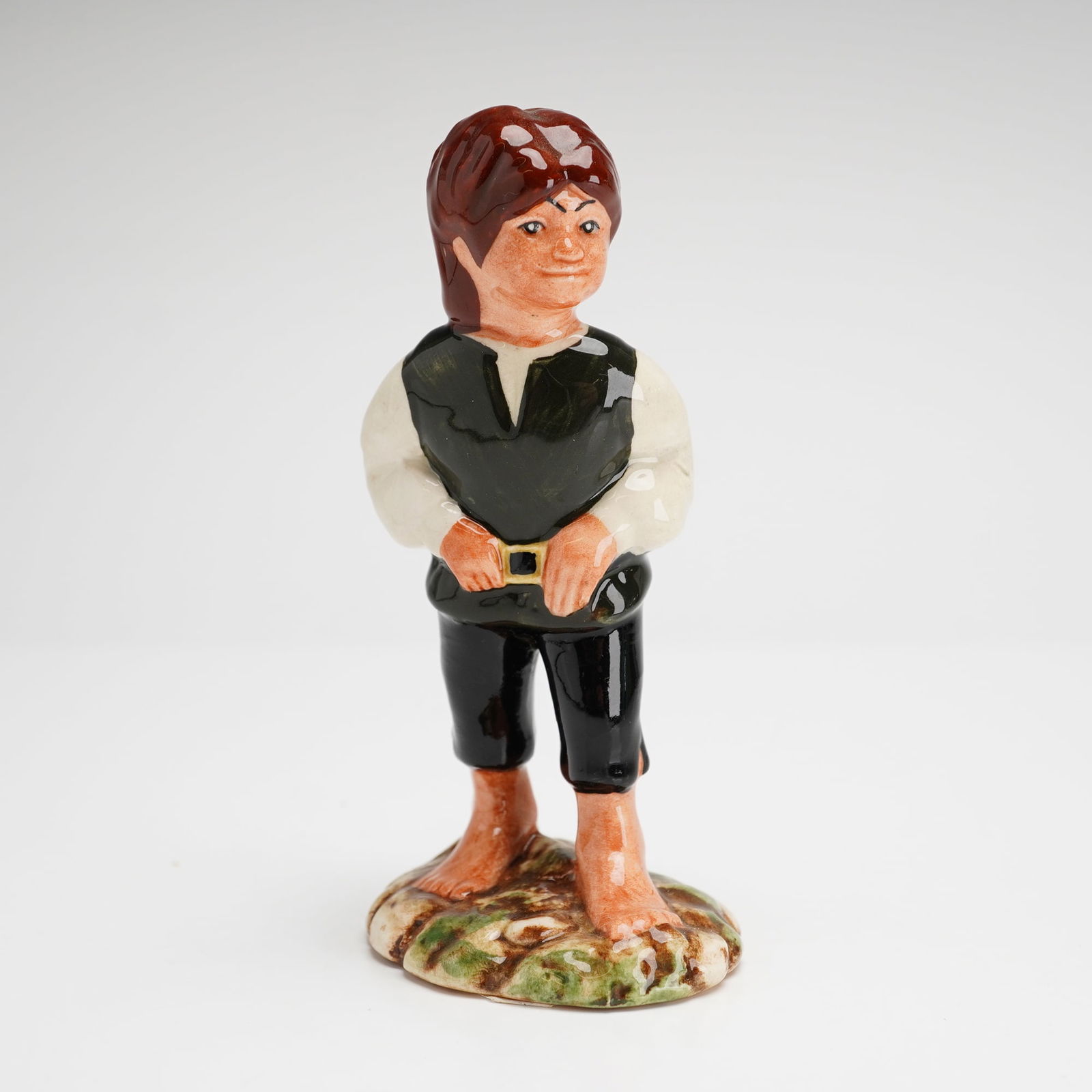 Royal Doulton Middle Earth Lord of the Rings Figurine, Frodo HN2912: A Royal Doulton figurine of the character Frodo, model HN2912, from the Mid Earth series. This hand-painted glazed ceramic figure is depicted with reddish-brown hair, wearing a white long-sleeved shir